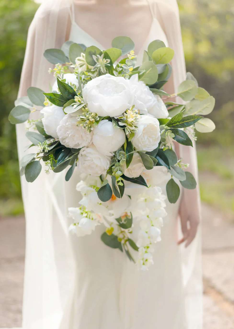 Cascading bridal bouquet of white flowers with lush green foliage accents