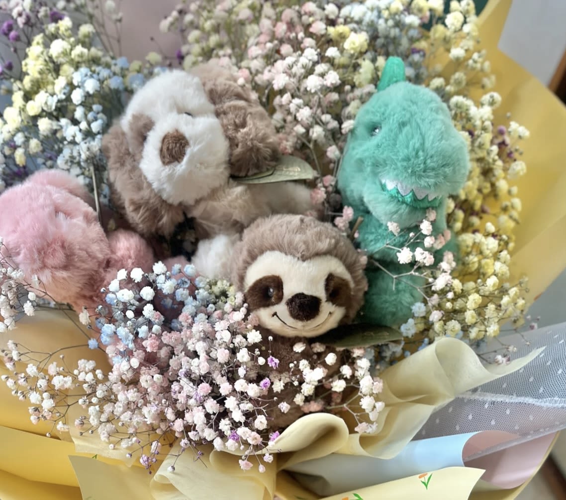 Bouquet of pastel baby’s breath surrounding small plush animals wrapped in yellow paper