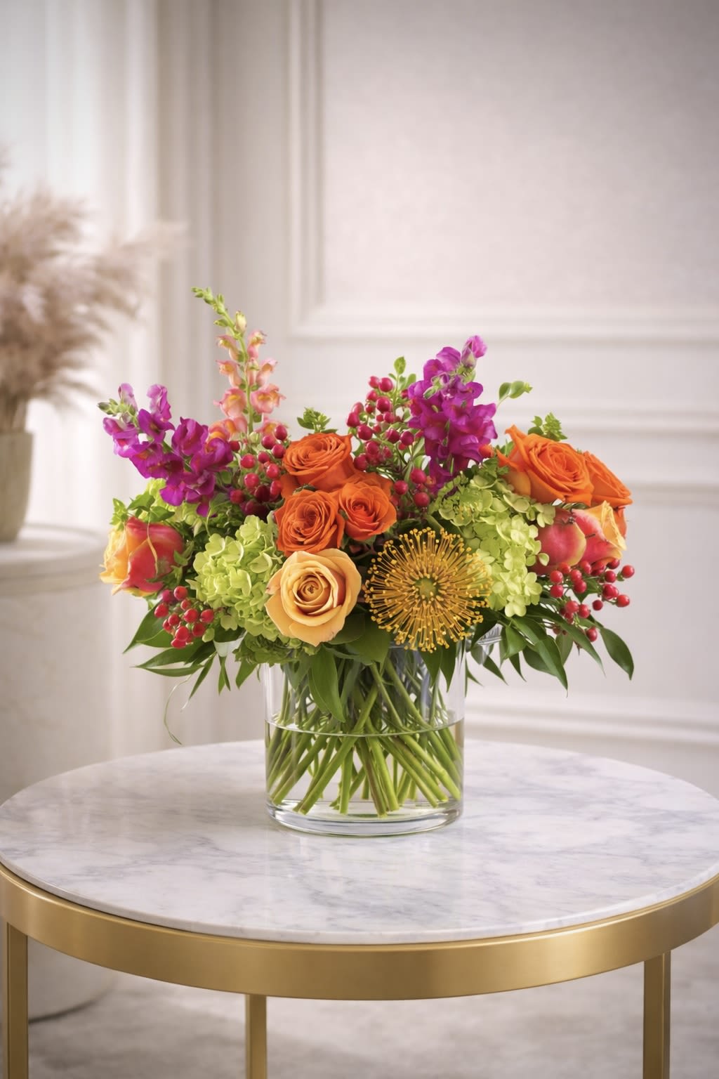Bright arrangement of orange roses, green hydrangeas, and pink snapdragons in a clear glass vase