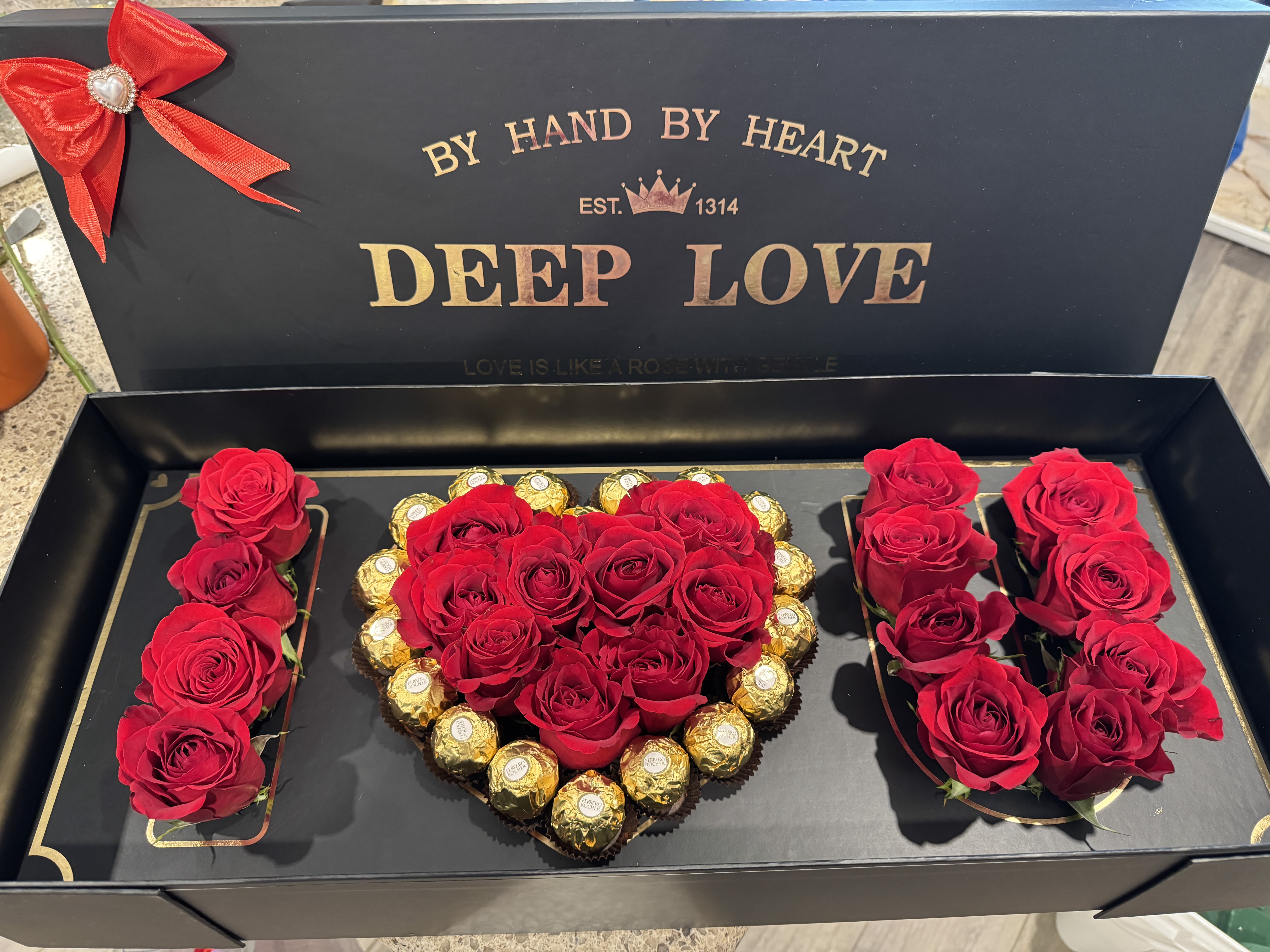 Red roses and chocolates arranged in a heart-shaped gift box
