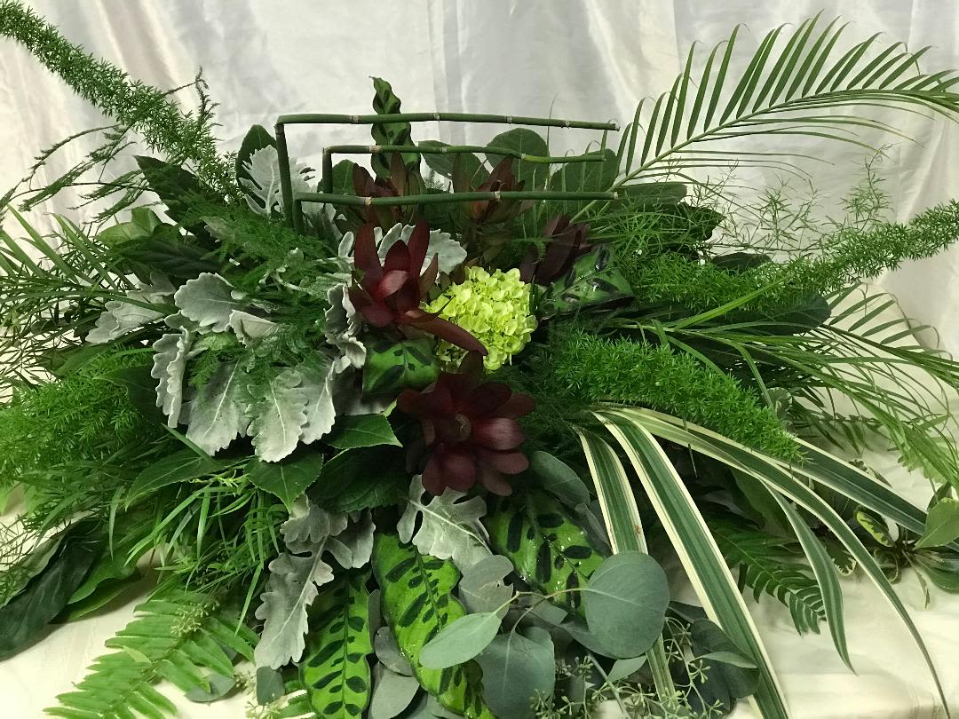 Large green tropical foliage arrangement with burgundy accents