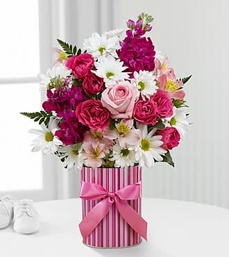 The FTD® Little Miracle™ Bouquet - Girl - LMGS  The FTD® Little Miracle™ Bouquet is the perfect way to welcome the newborn into the world and help the family celebrate on this most momentous occasion! Bringing together pink roses, hot pink spray roses, pink Peruvian Lilies, white traditional daisies, fragrant fuchsia stock and lush greens, this stunning flower bouquet exudes warm wishes and sweet sentiments. Presented in a designer striped pink container accented with a satin pink ribbon on the front, this beautiful mixed flower arrangement will be a memorable gift for the new family.