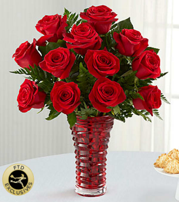 The FTD® In Love with Red Roses™ Bouquet - There's no mistaking your meaning when you express what's in your heart with this simply spectacular gathering of vibrant red roses. Love will most definitely be in the air when this extraordinary bouquet is delivered to that certain someone on Valentine's Day or on any day when romance is on your agenda. Beautifully hand-arranged in a heavy, red glass, contemporary-styled vase, this bouquet is certain to set hearts aflutter. Your purchase includes a complimentary personalized gift message.