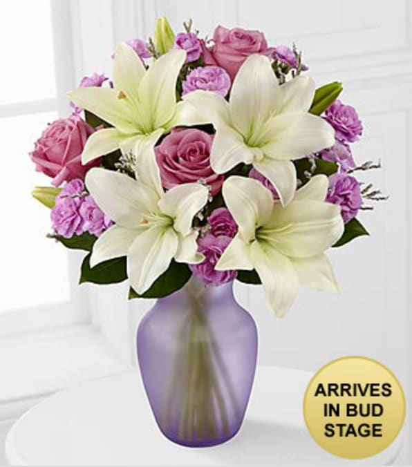Lavender Twilight Mixed Flower Bouquet - VASE INCLUDED - Picked fresh from the farm to delight your special recipient with its elegant beauty, the Lavender Twilight Mixed Flower Bouquet is set to send your warmest greetings to friends and family near and far. Hand gathered in select floral farms and bringing together the enchanting color combination of lavender and white, this gorgeous flower arrangement has been picked fresh for you to help you celebrate a birthday, or express your thank you or get well wishes. This bouquet includes the following: white Asiatic Lilies, lavender roses, lavender mini carnations, lavender limonium, and an assortment of lush greens. Presented with a lavender glass vase.  GOOD bouquet is approximately 16"H x 13"W. BETTER bouquet is approximately 17"H x 15"W. *May Arrive in Bud Stage. Your purchase includes a complimentary personalized gift message.