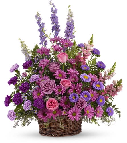 Purple and pink mixed flower arrangement in a wicker basket