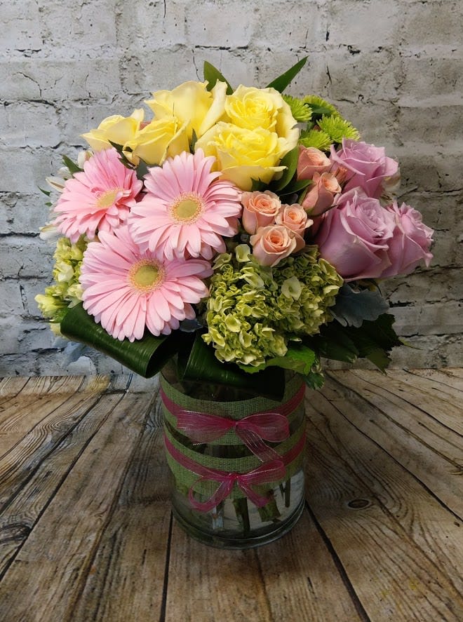 Bouquet of pink and yellow flowers in a glass vase with ribbon