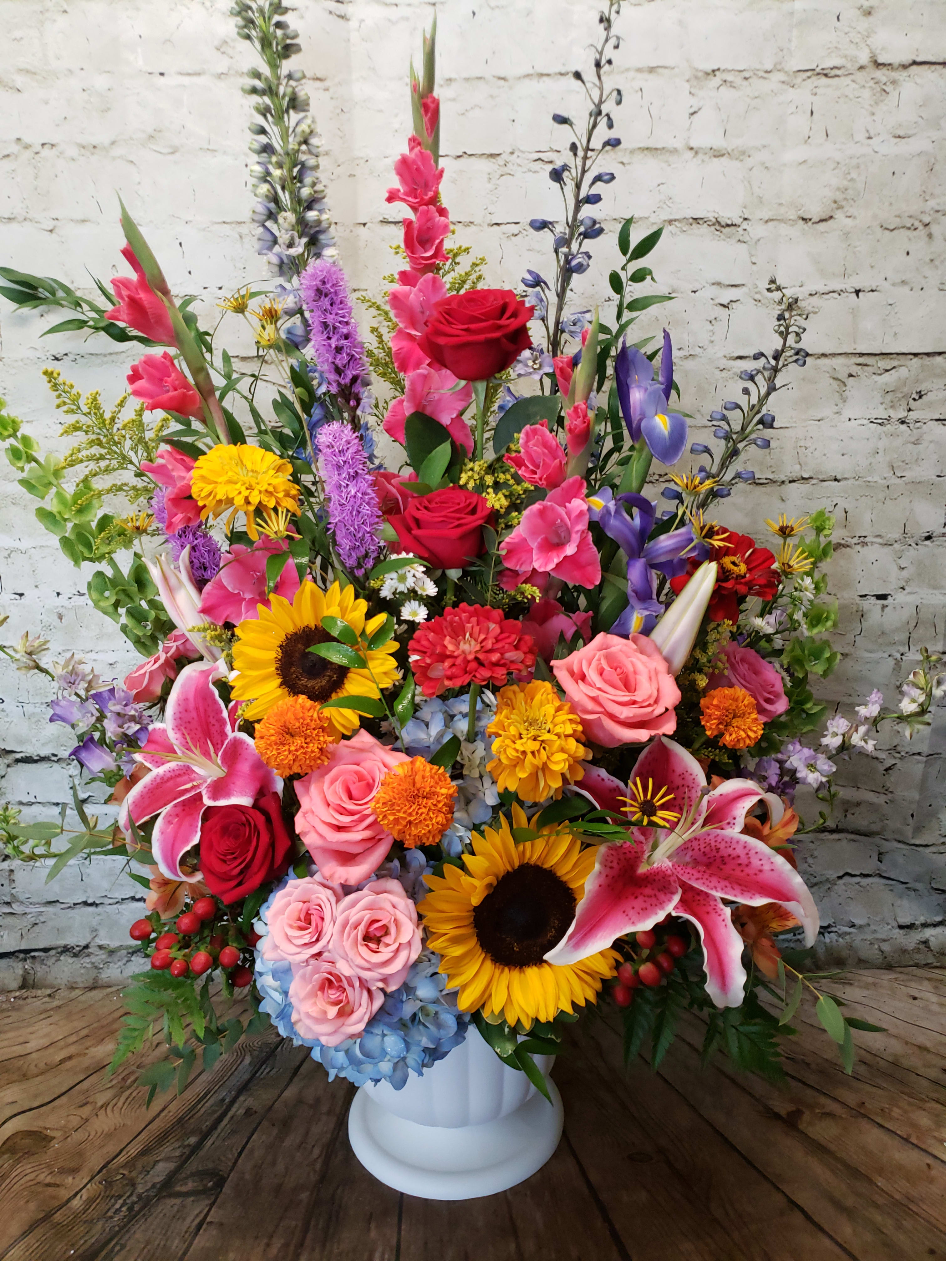 Large mixed flower arrangement in a white pedestal vase