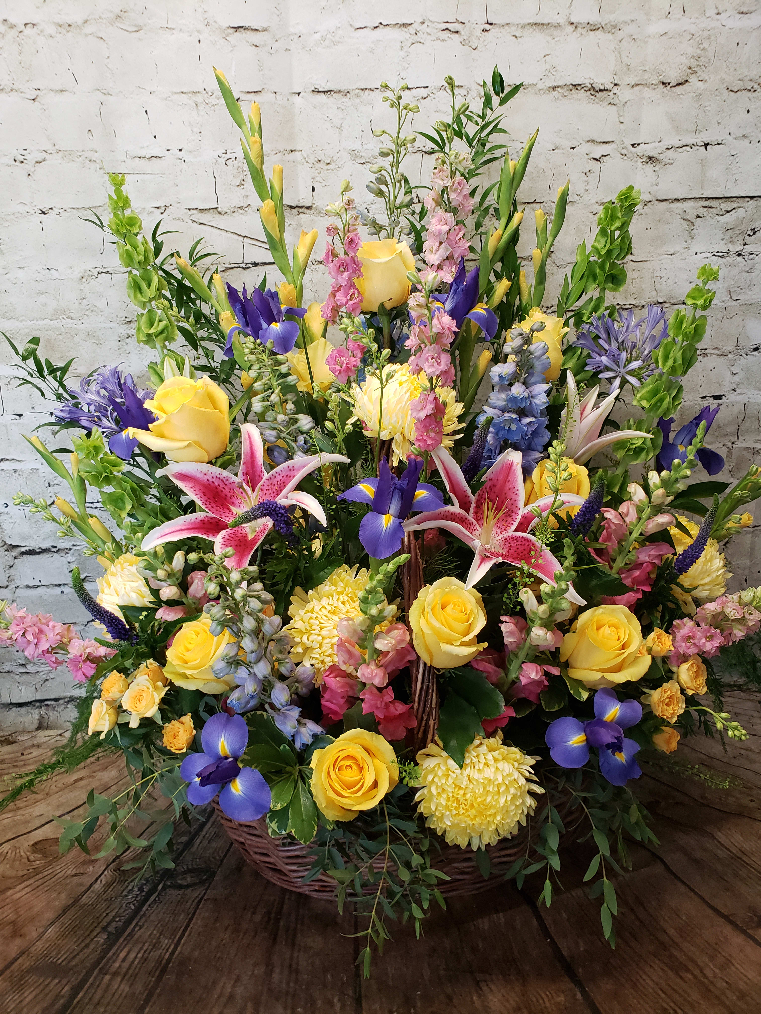 Large basket arrangement with yellow roses, pink lilies, and purple irises