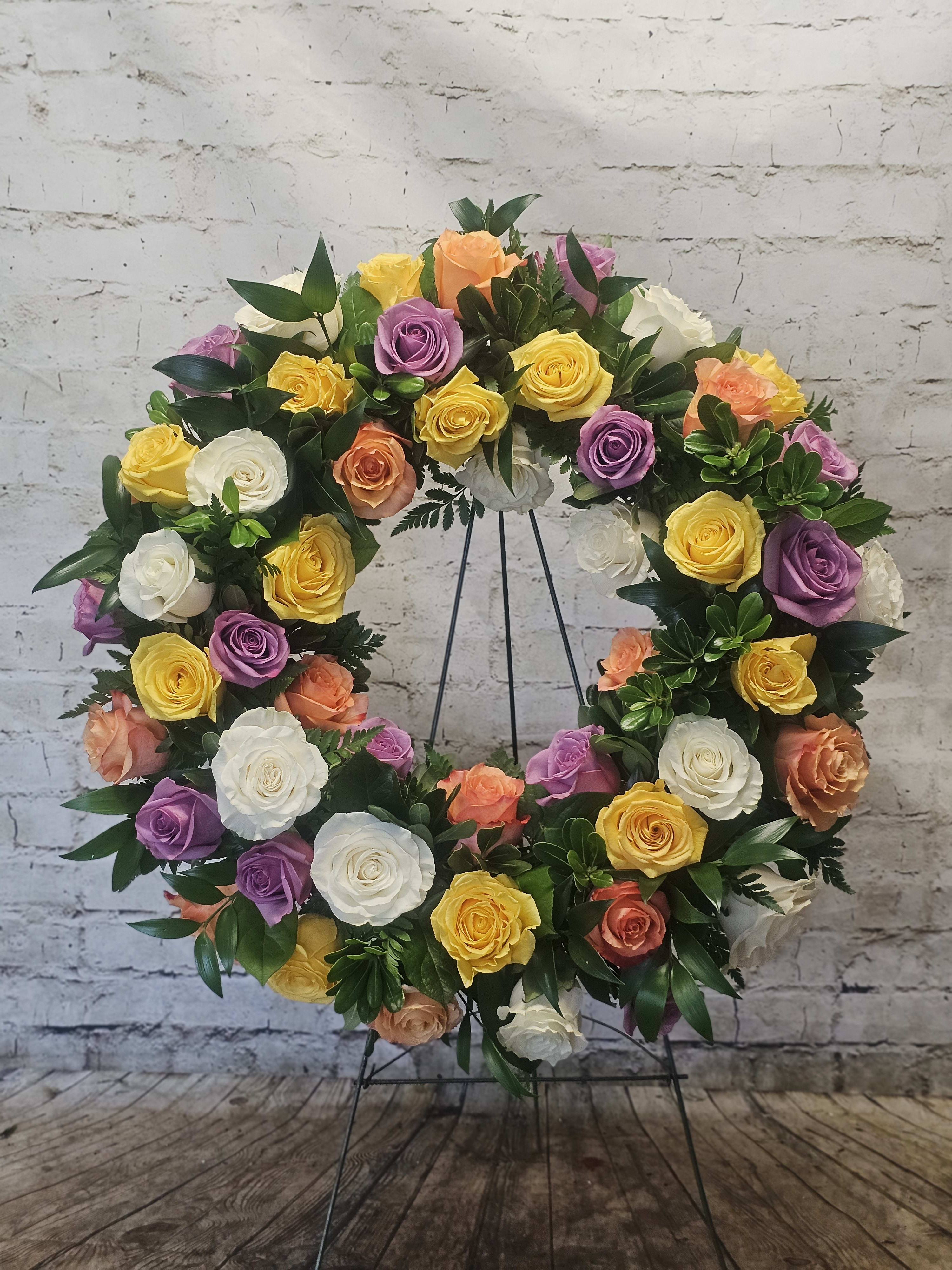 Circular wreath of multicolored roses on a metal stand