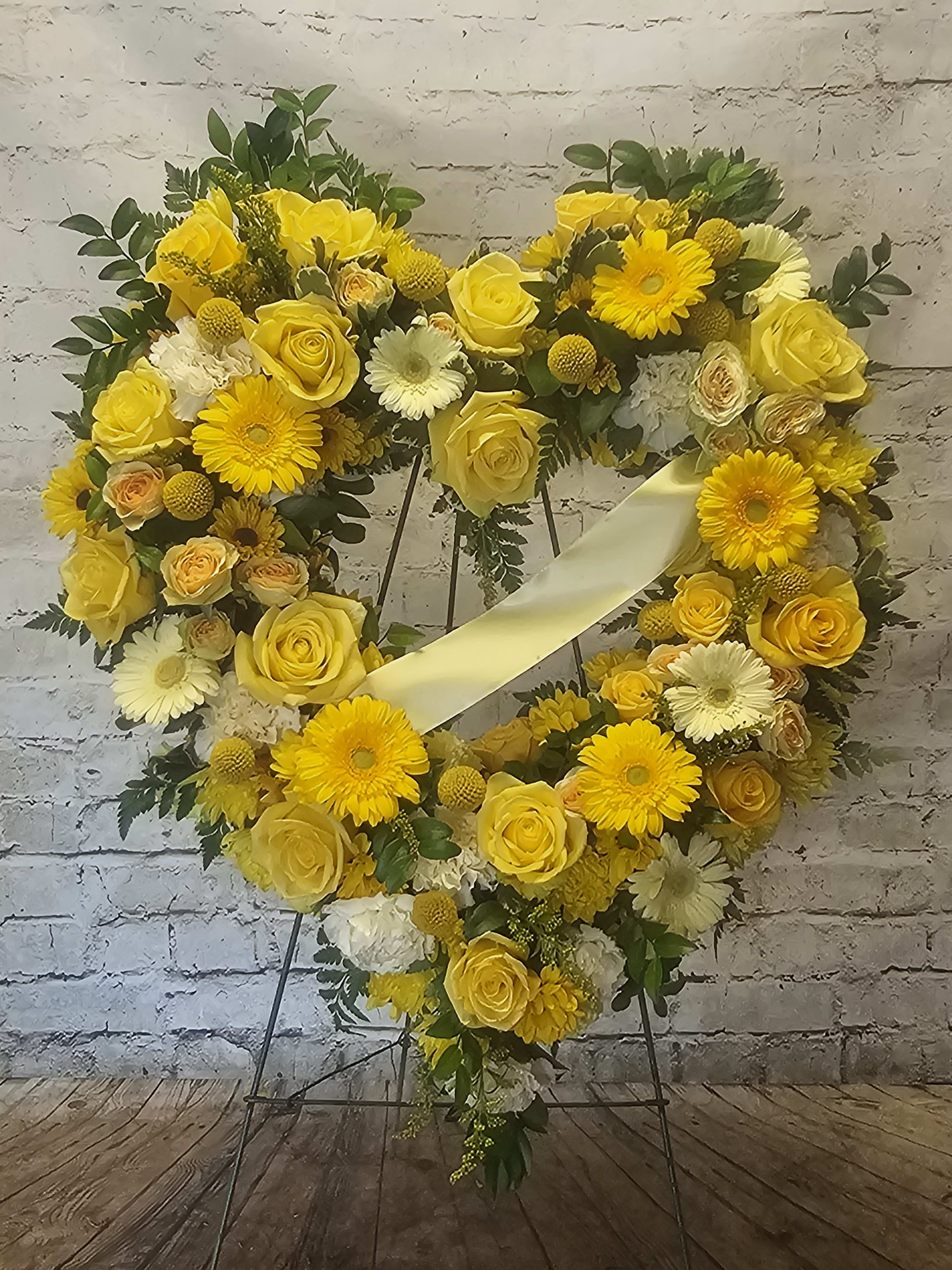 Yellow floral heart wreath on a stand with a pale ribbon