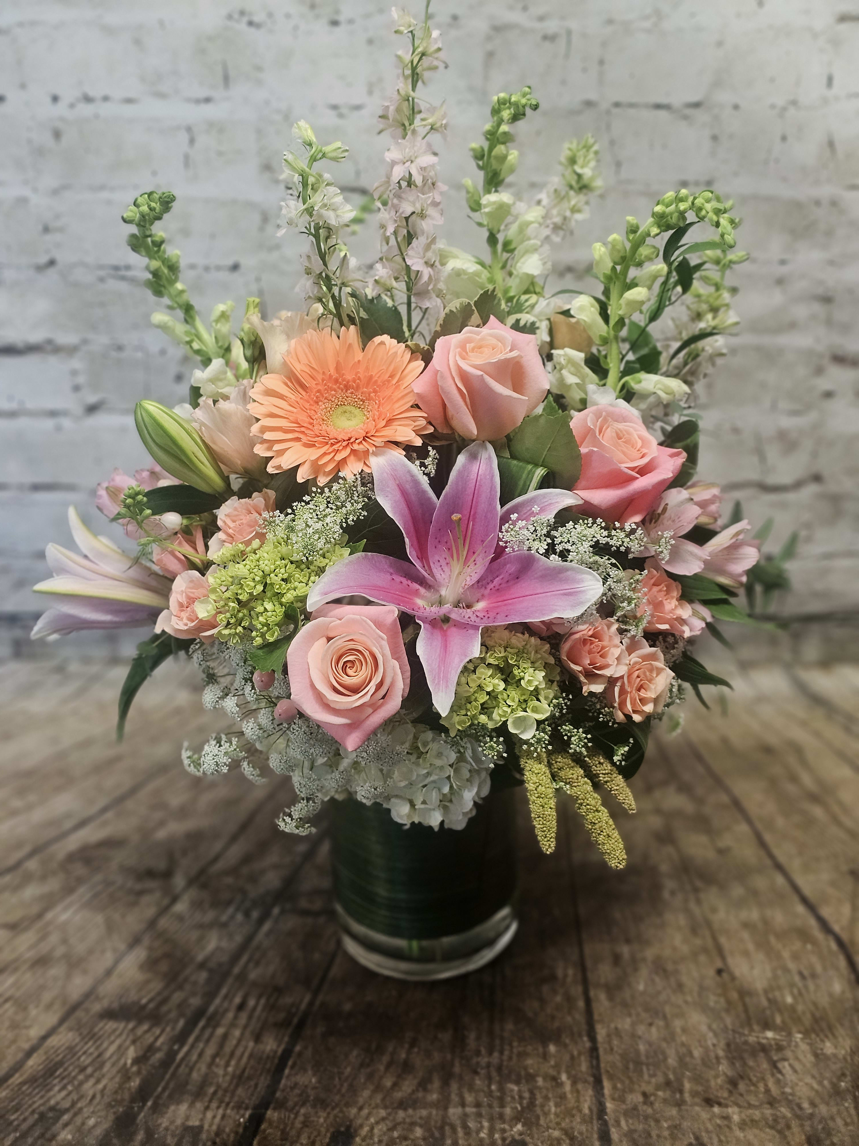 Mixed bouquet with pink lilies, roses, and peach gerbera daisies in a vase