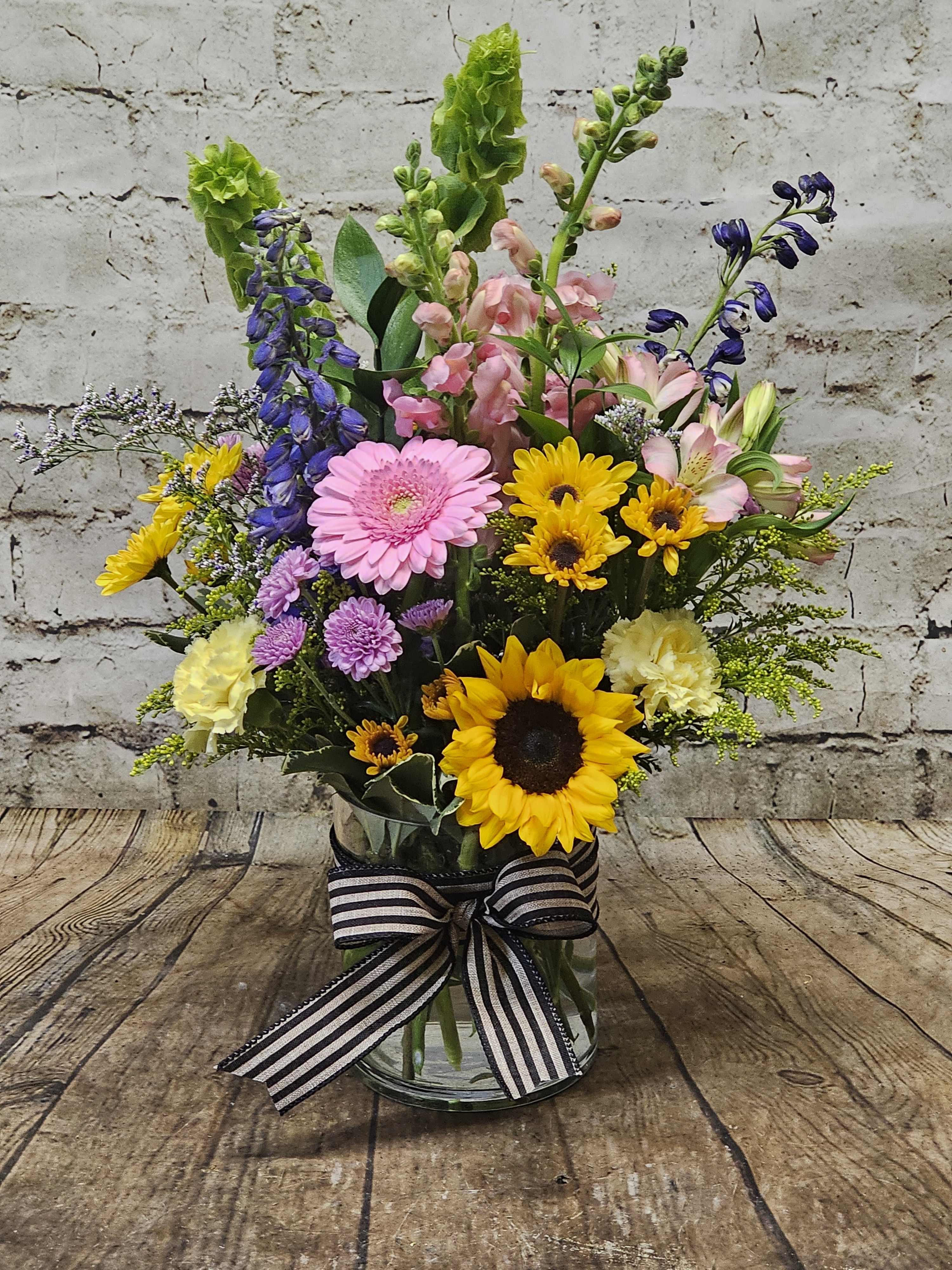 Mixed bouquet in a glass vase with sunflowers, gerberas, and snapdragons
