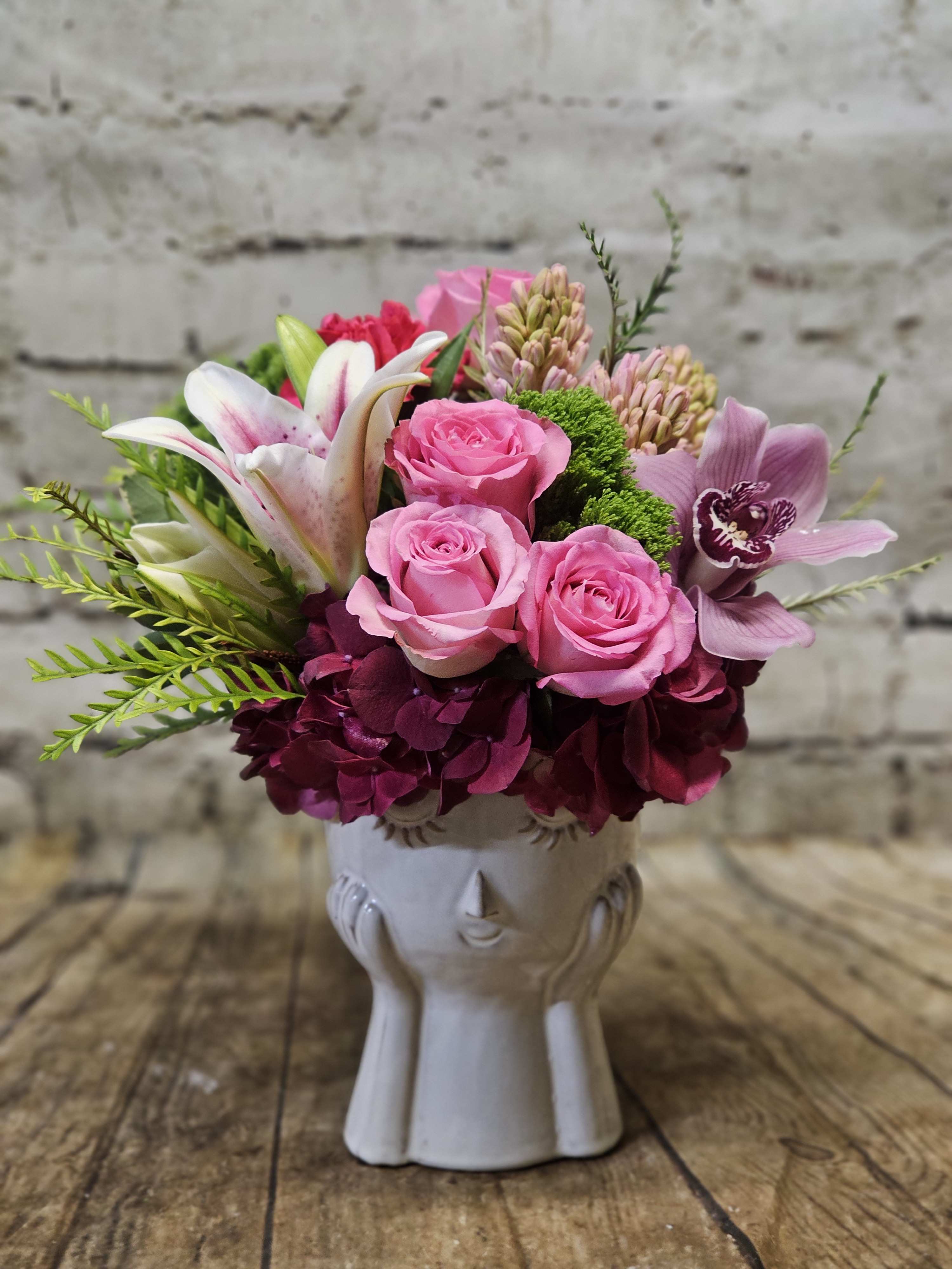 Pink roses and lilies arranged in a white ceramic vase