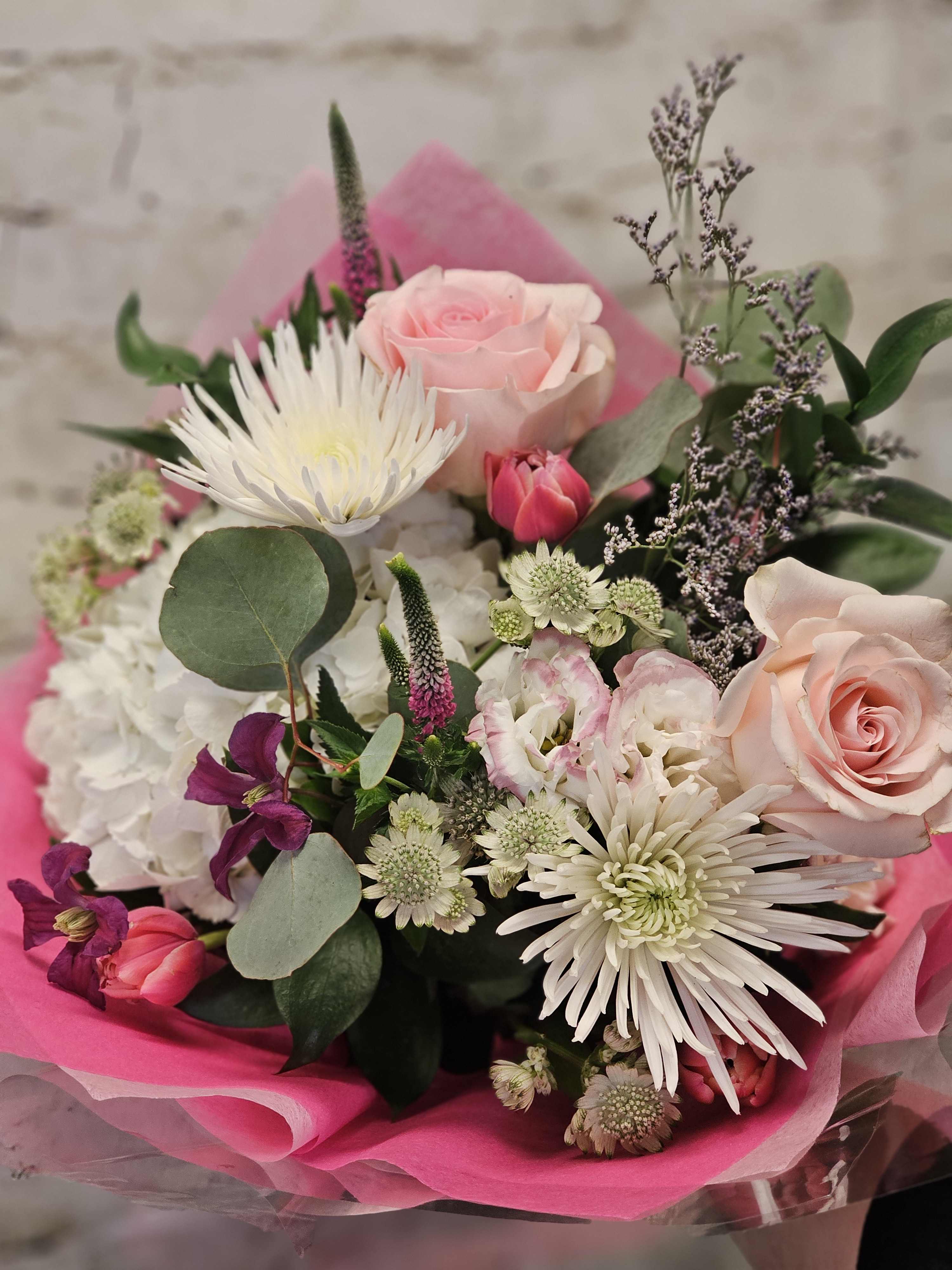 Bouquet of pink and white flowers wrapped in bright pink paper