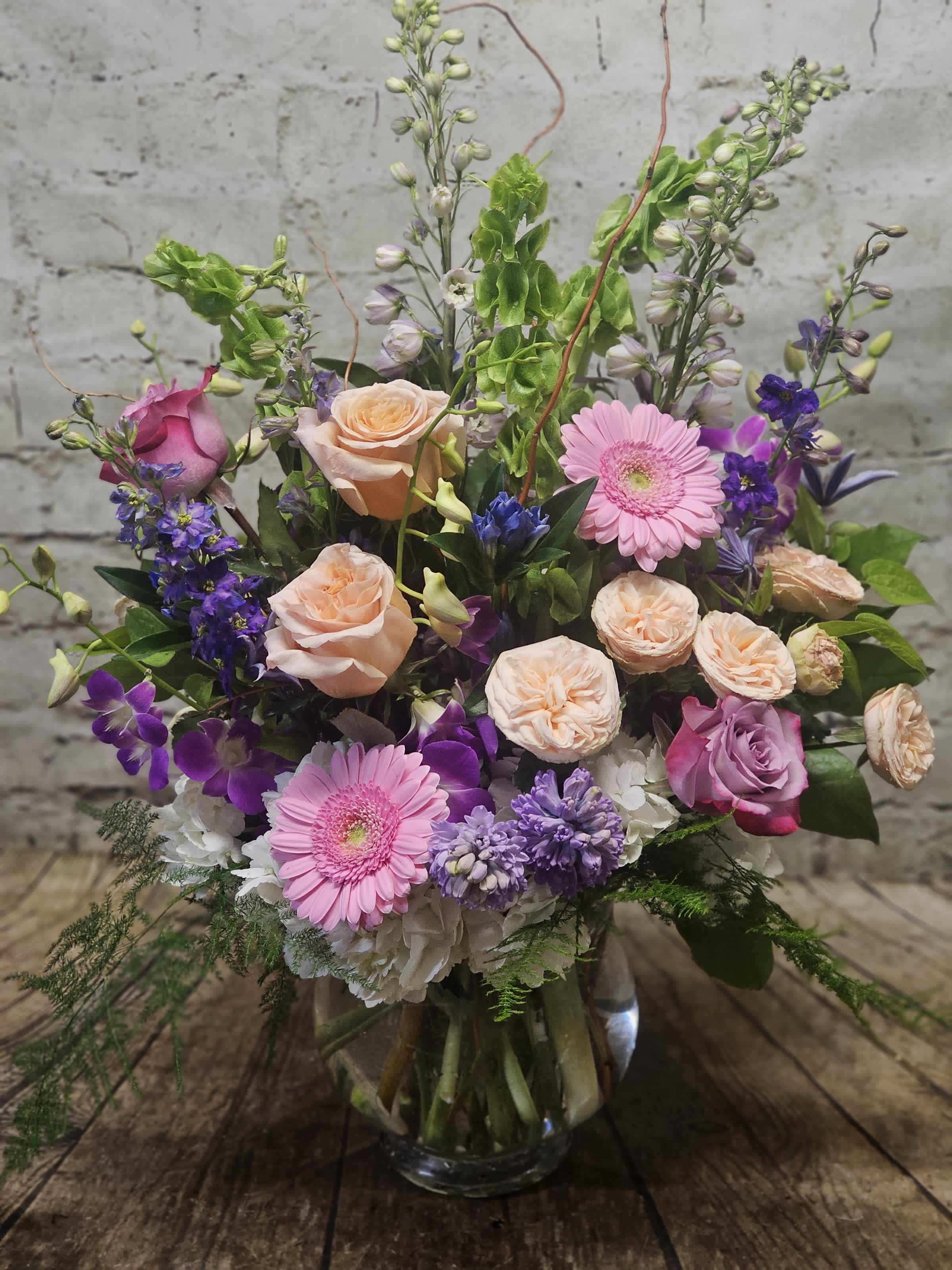Mixed pink, purple, and peach flowers arranged in a glass vase