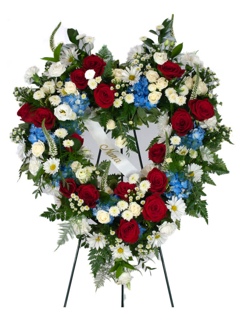Heart-shaped standing wreath of red, white, and blue flowers on an easel