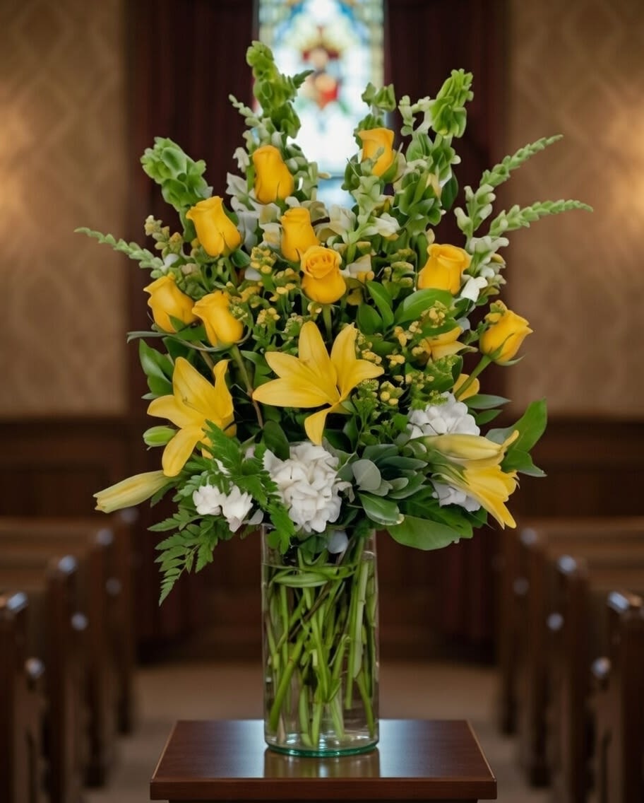 Yellow roses and lilies arranged in a clear glass vase