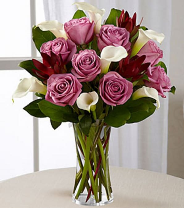Lavender Beauty Bouquet - VASE INCLUDED - Picked fresh from the farm to create that perfect impression on your special recipient, the Lavender Beauty Bouquet blooms with an unforgettable grace and charm to help you express your every emotion. Hand gathered in select floral farms and bringing together the enchanting color combination of lavender, white, and green, this stunning floral arrangement has been picked fresh for you to celebrate a birthday, anniversary, or to let them know how much you appreciate their place in your life. This bouquet includes: lavender roses, white mini calla lilies, and an assortment of lush greens. Available with a selection of vases to fit your gifting needs. GOOD bouquet includes 15 stems with clear glass vase. Approximately 16"H x 15"W/ BETTER bouquet includes 19 stems with clear glass vase. Approximately 17"H x 15"W. BEST bouquet includes 23 stems with clear glass vase. Approximately 18"H x 16"W. Your purchase includes a complimentary personalized gift message.