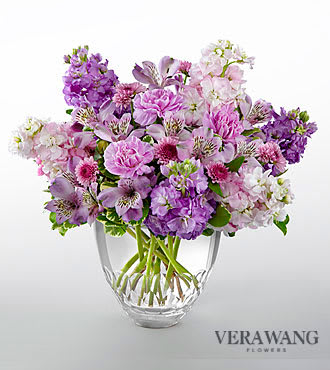 The FTD® Delightful Discoveries™ Bouquet by Vera Wang - V19S  FTD® proudly presents the Delightful Discoveries™ by Vera Wang. Create a moment your special recipient will hold dear in their heart with this captivating flower arrangement exuding an alluring style and sweet fragrance. Lovely in shades of lavender, this mixed flower bouquet employs purple stock, purple Peruvian lilies, lavender carnations, light purple stock and lavender chrysanthemums accented with lush vibrant greens to create a simply stunning display. Presented with a clear modern glass vase to give it an extra touch of sophistication, this flower arrangement will make an exceptional thank you, get well, or happy birthday gift. GOOD bouquet is approximately 14"H x 14"W.
