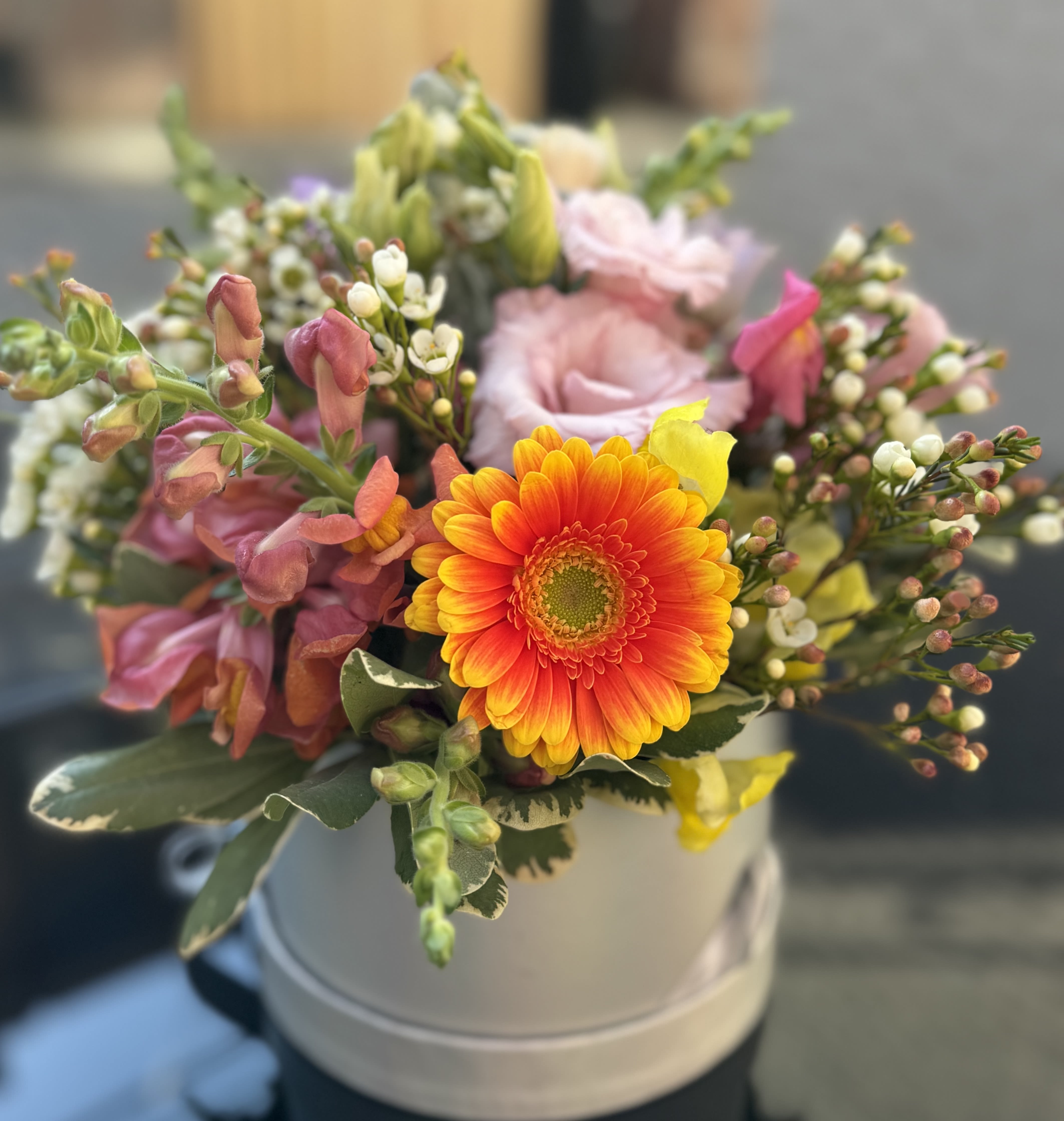 Mixed bouquet with a bright orange gerbera daisy in a white hatbox