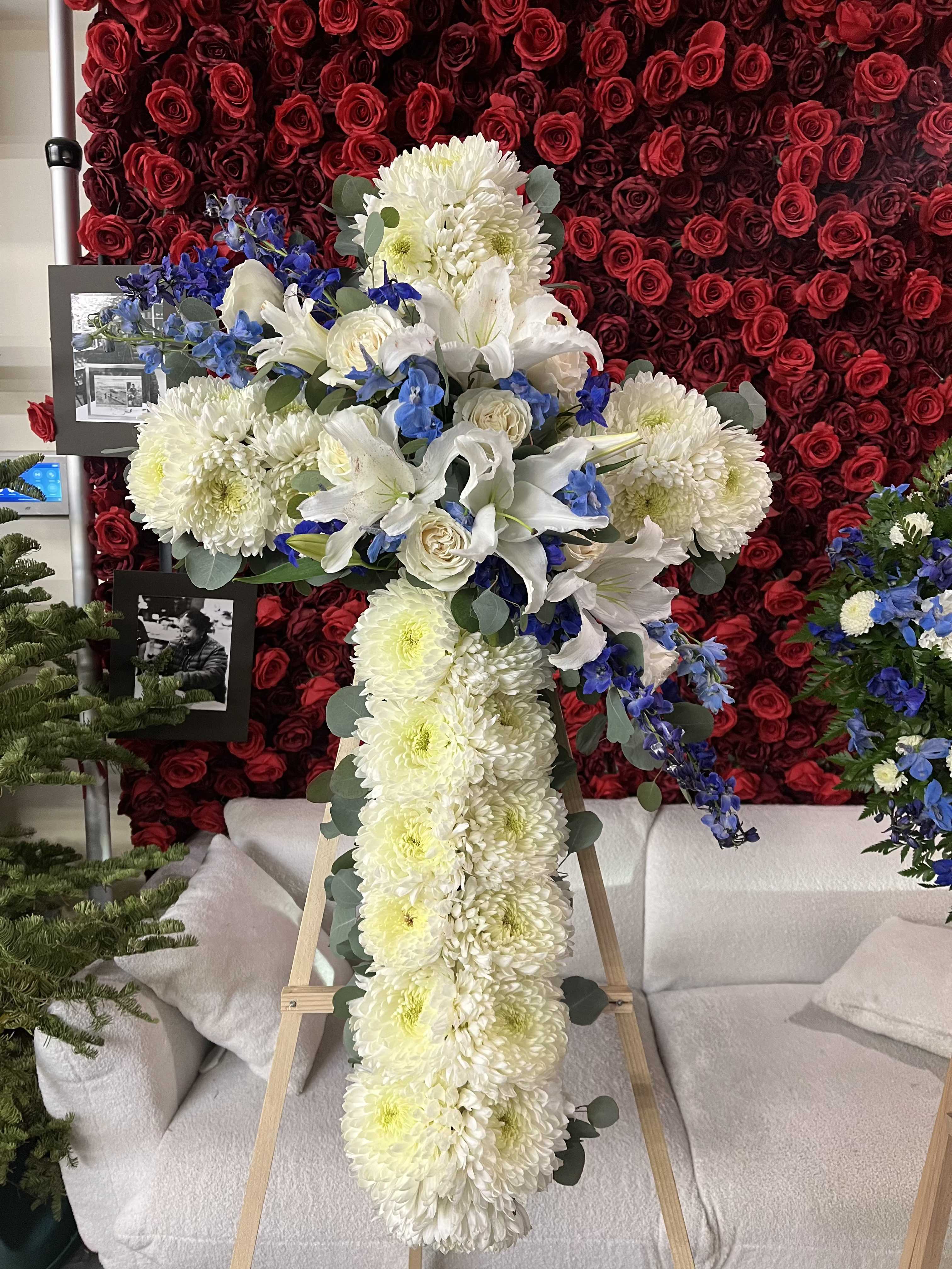 Large white floral cross on an easel with blue accents