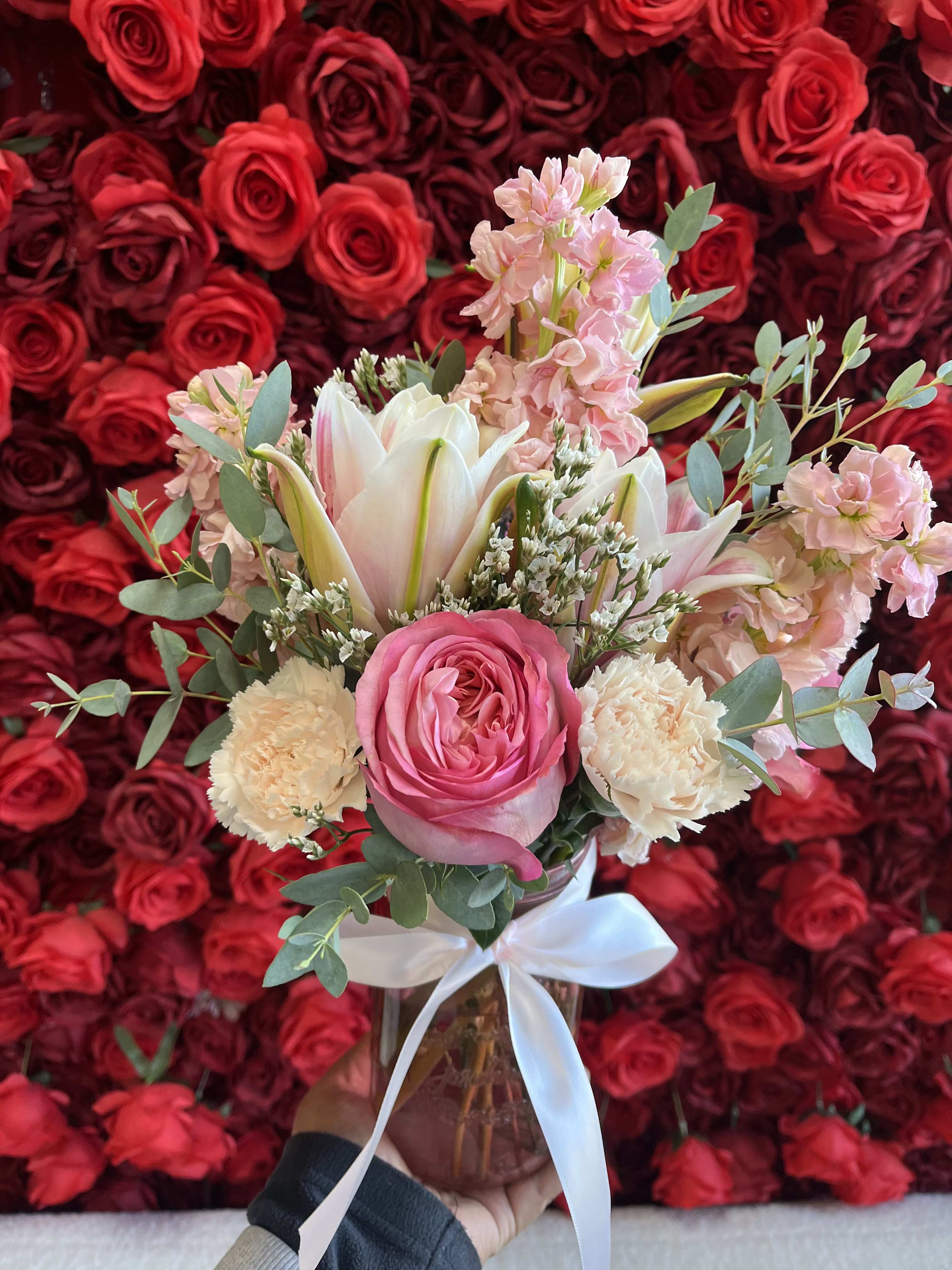 Pink and white bouquet in a glass vase with a white ribbon
