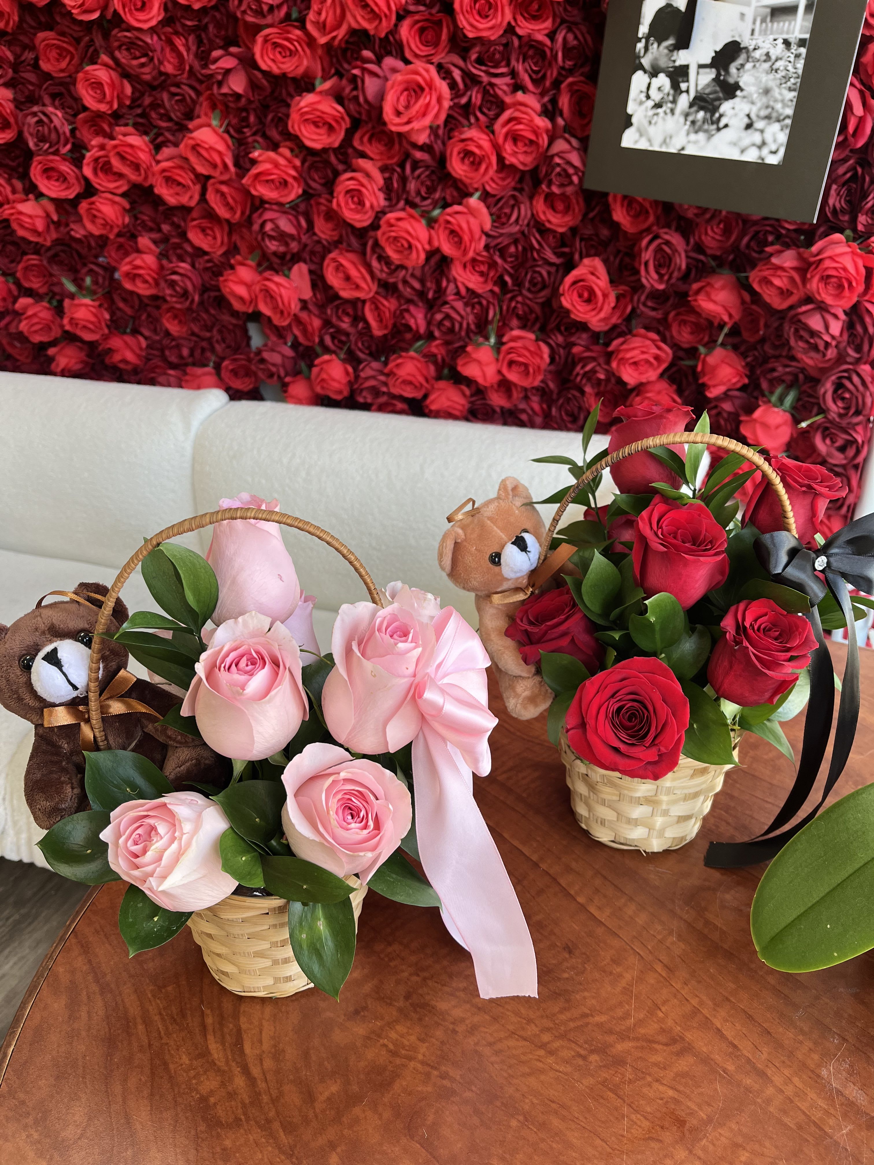 Two small rose baskets with teddy bears and ribbons on a table