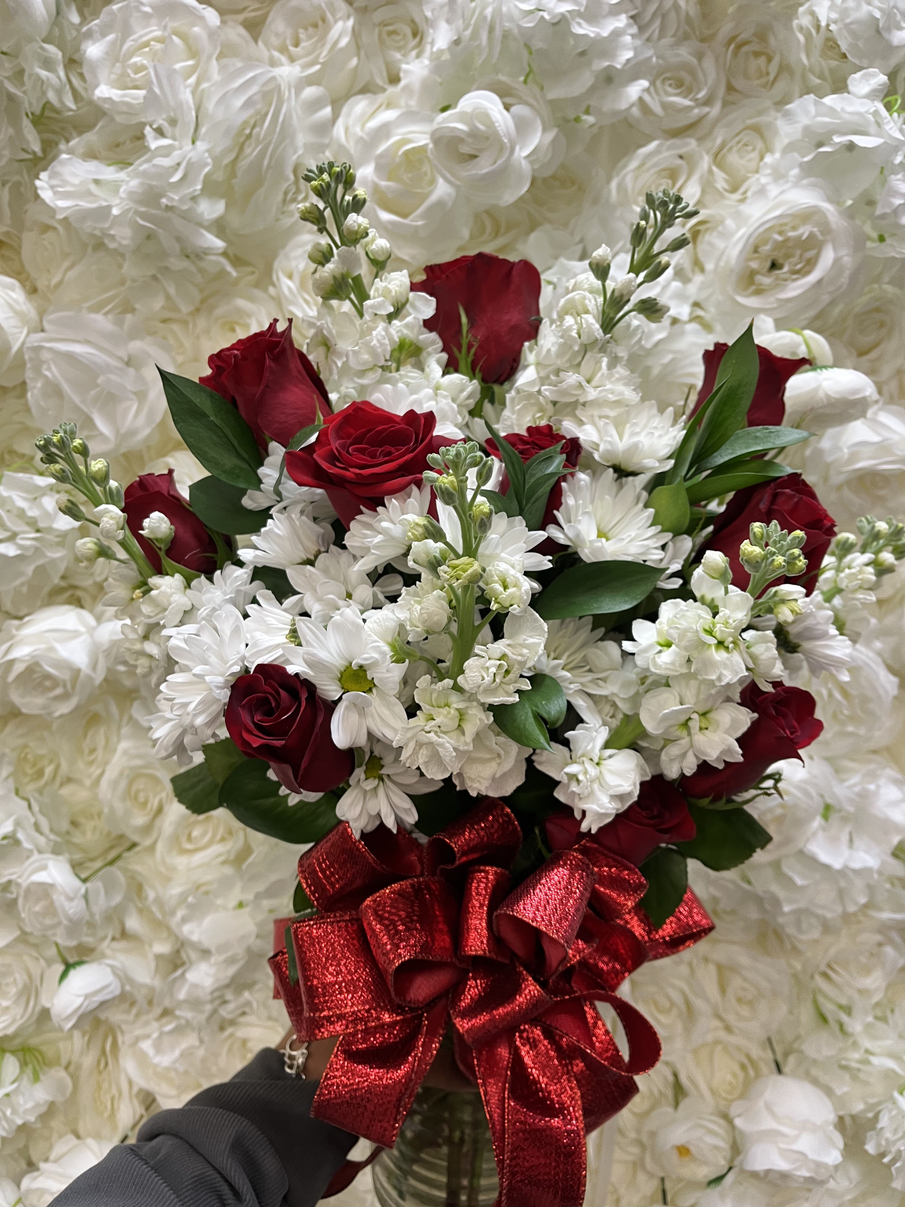 Red roses and white daisies in a bouquet with a red ribbon