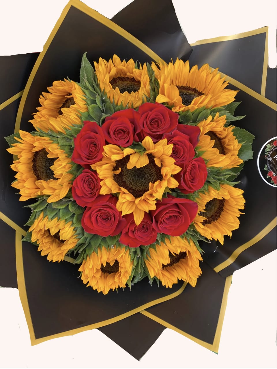 Bouquet of red roses and sunflowers wrapped in black paper with gold trim
