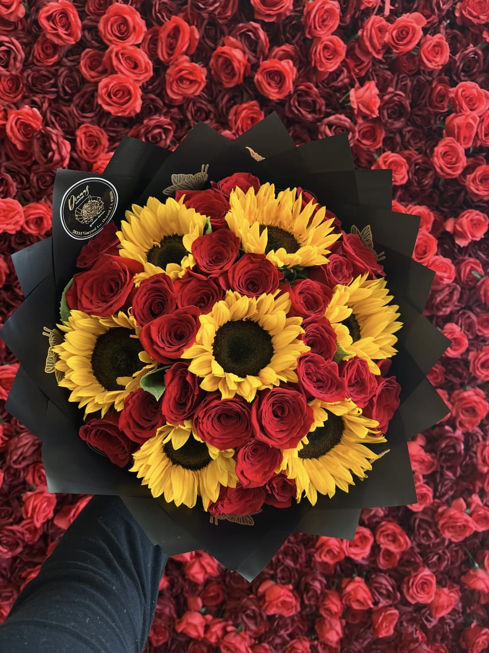 Bouquet of red roses and yellow sunflowers wrapped in black paper