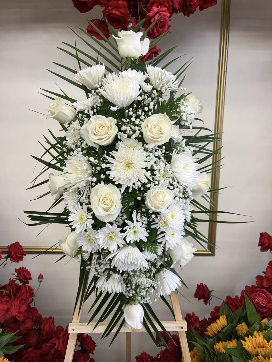 White roses and chrysanthemums arranged on a standing easel.