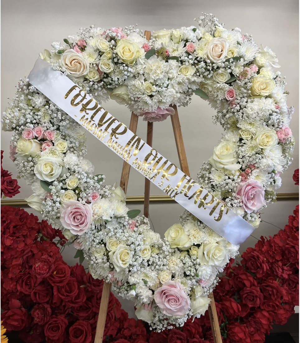 Heart-shaped floral wreath with white and pink roses on an easel