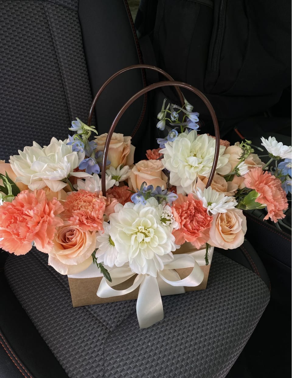 Peach roses and white dahlias in a gift basket with a ribbon