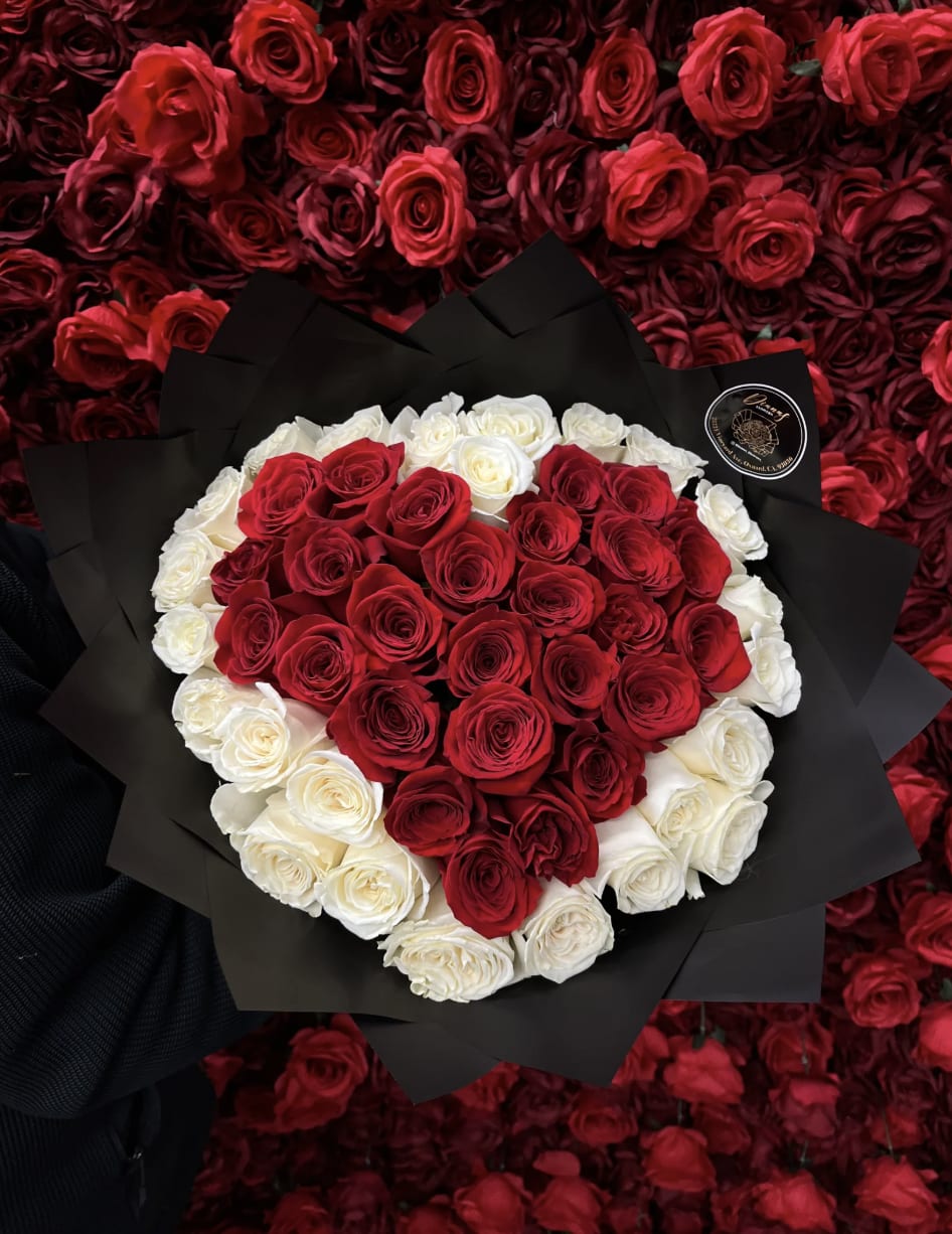 Heart-shaped bouquet of red and white roses wrapped in black paper