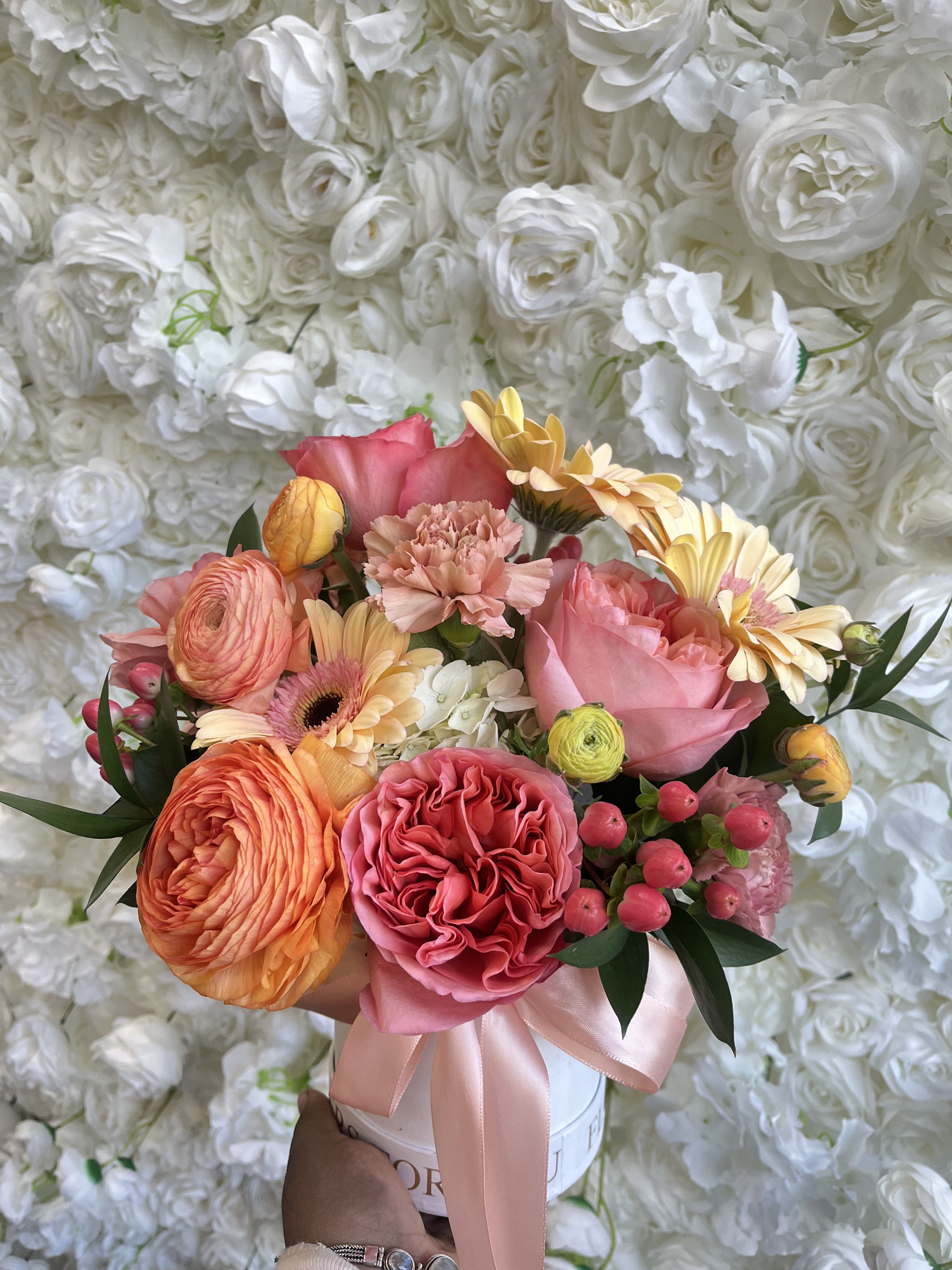 Mixed bouquet of pink, peach, and yellow flowers in a white box with a ribbon