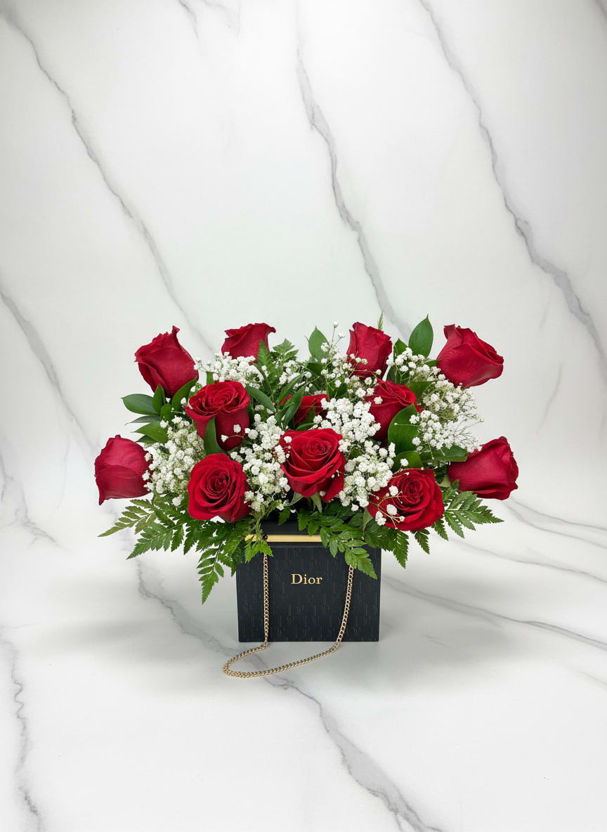 Red roses arranged in a black Dior gift box with a gold chain