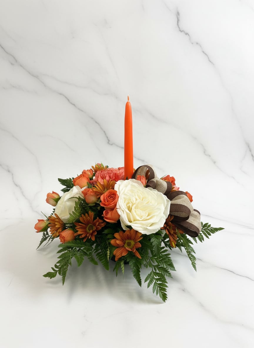 Orange floral centerpiece with a tall candle and ribbon bow