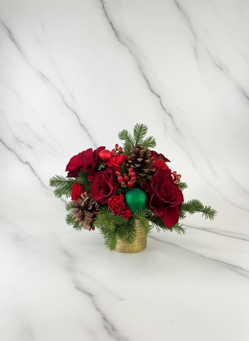 Red floral arrangement with pinecones and evergreen in a gold container