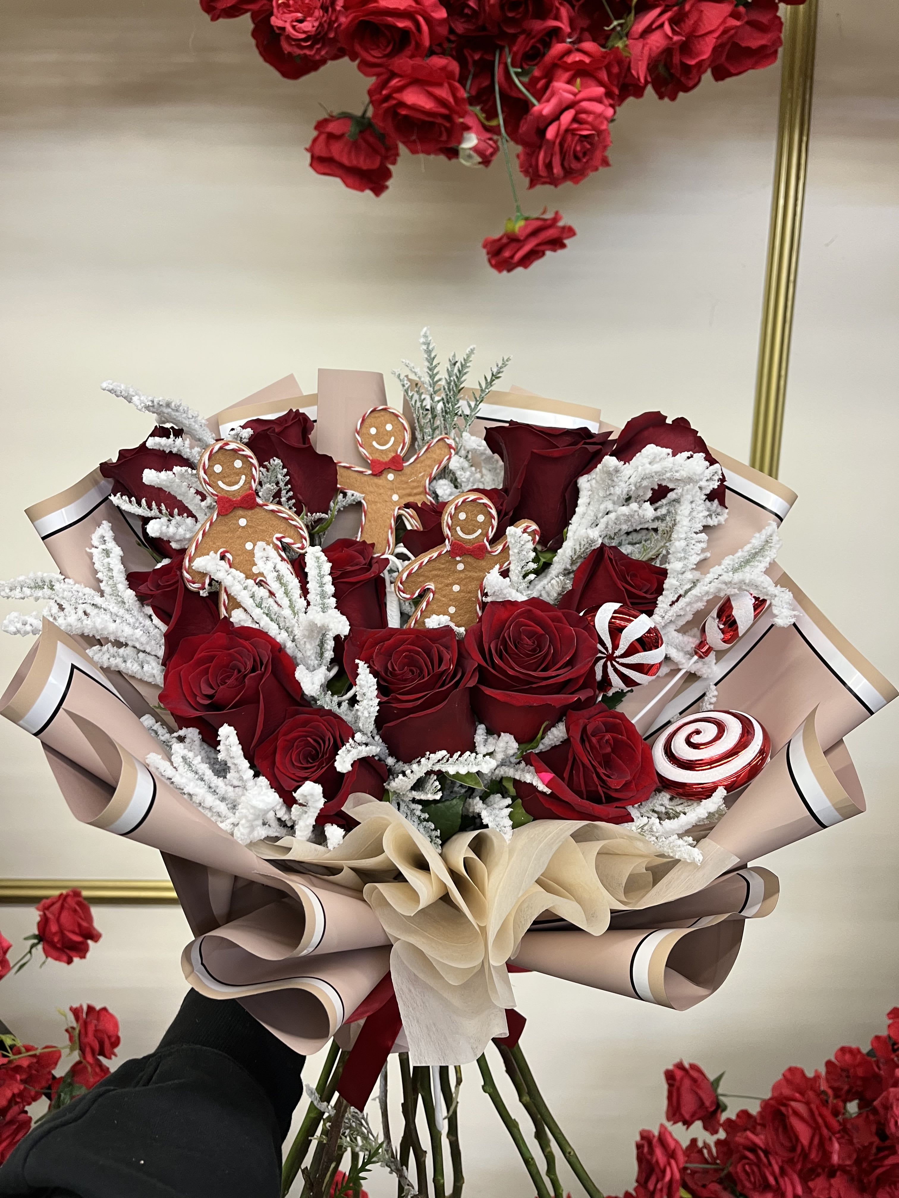 Bouquet of red roses with gingerbread decorations and candy accents