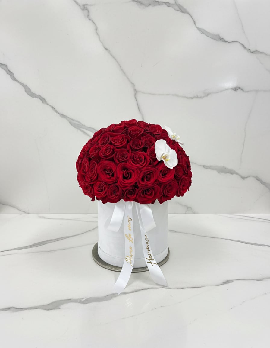 Round bouquet of red roses in a white hat box with white orchids