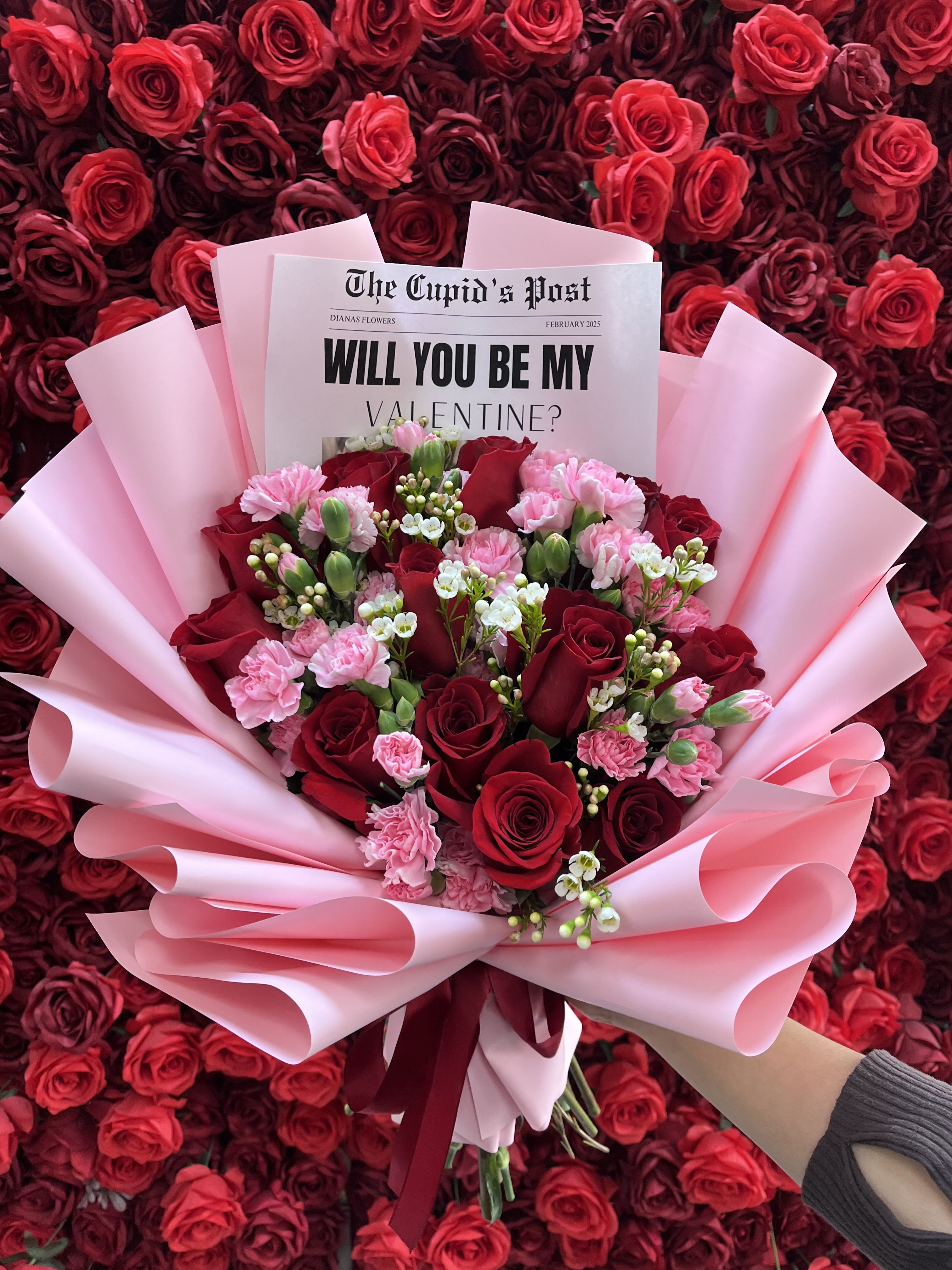 Bouquet of red roses and pink carnations wrapped in pink paper