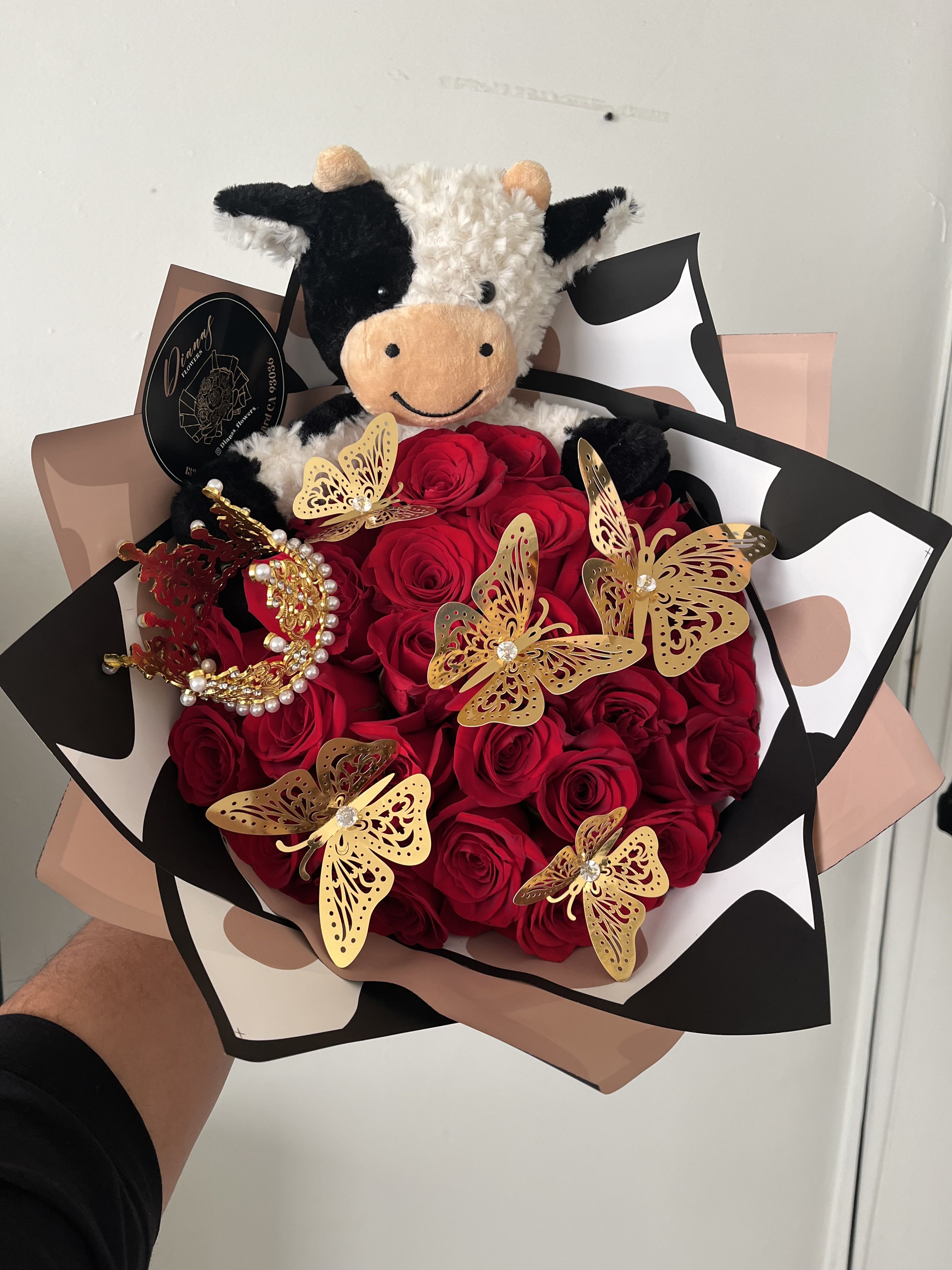Bouquet of red roses with a plush cow and gold butterfly decorations