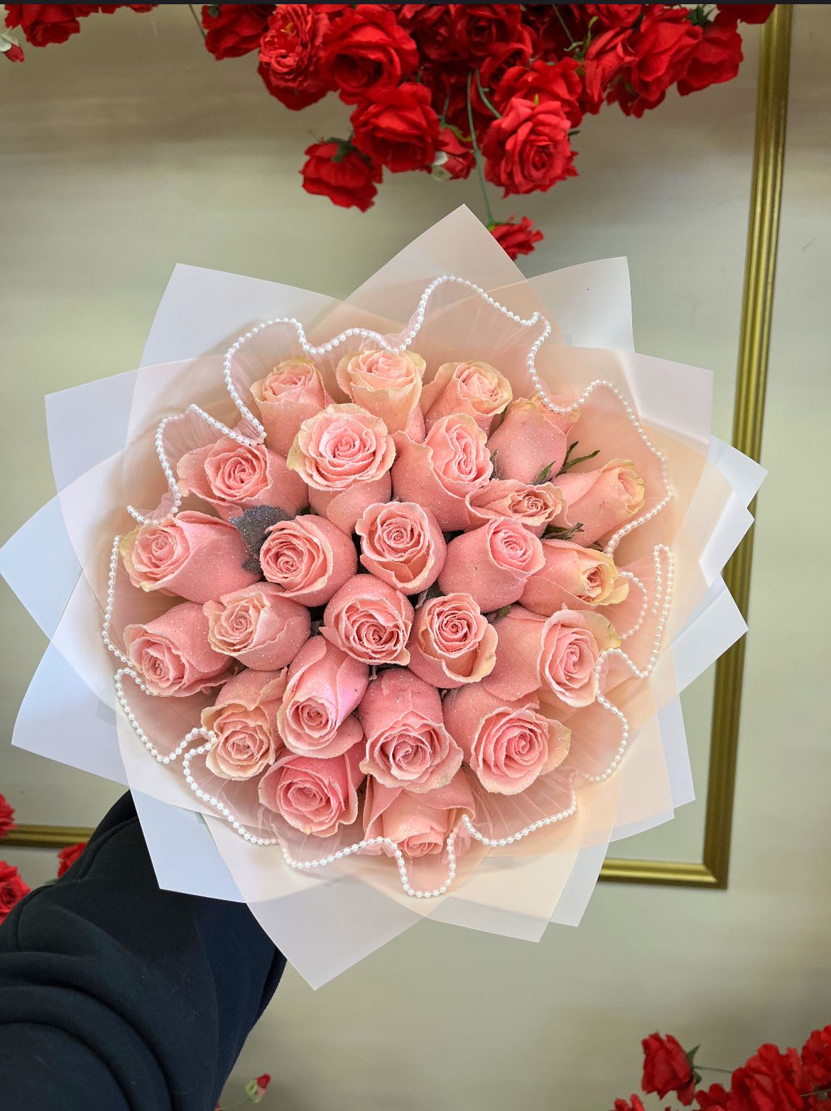 Bouquet of pink roses wrapped in pale paper with pearl trim