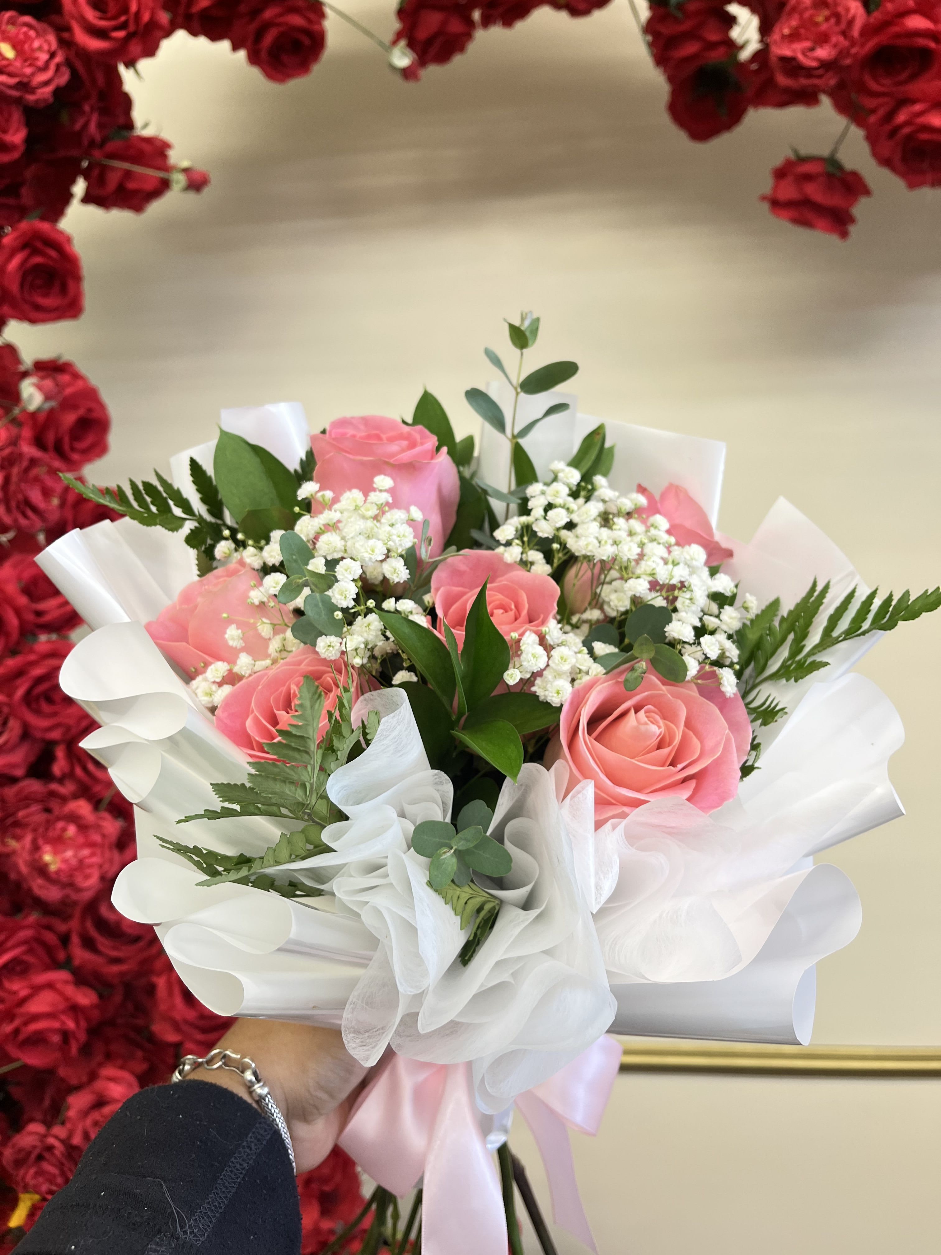 Pink roses in white wrapping with baby's breath and greenery