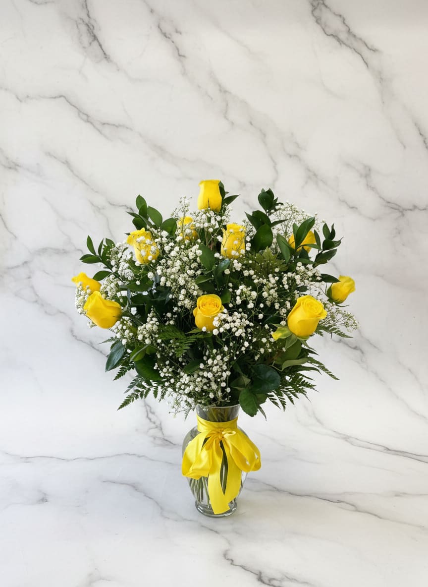 Yellow roses and baby's breath in a glass vase with a yellow ribbon