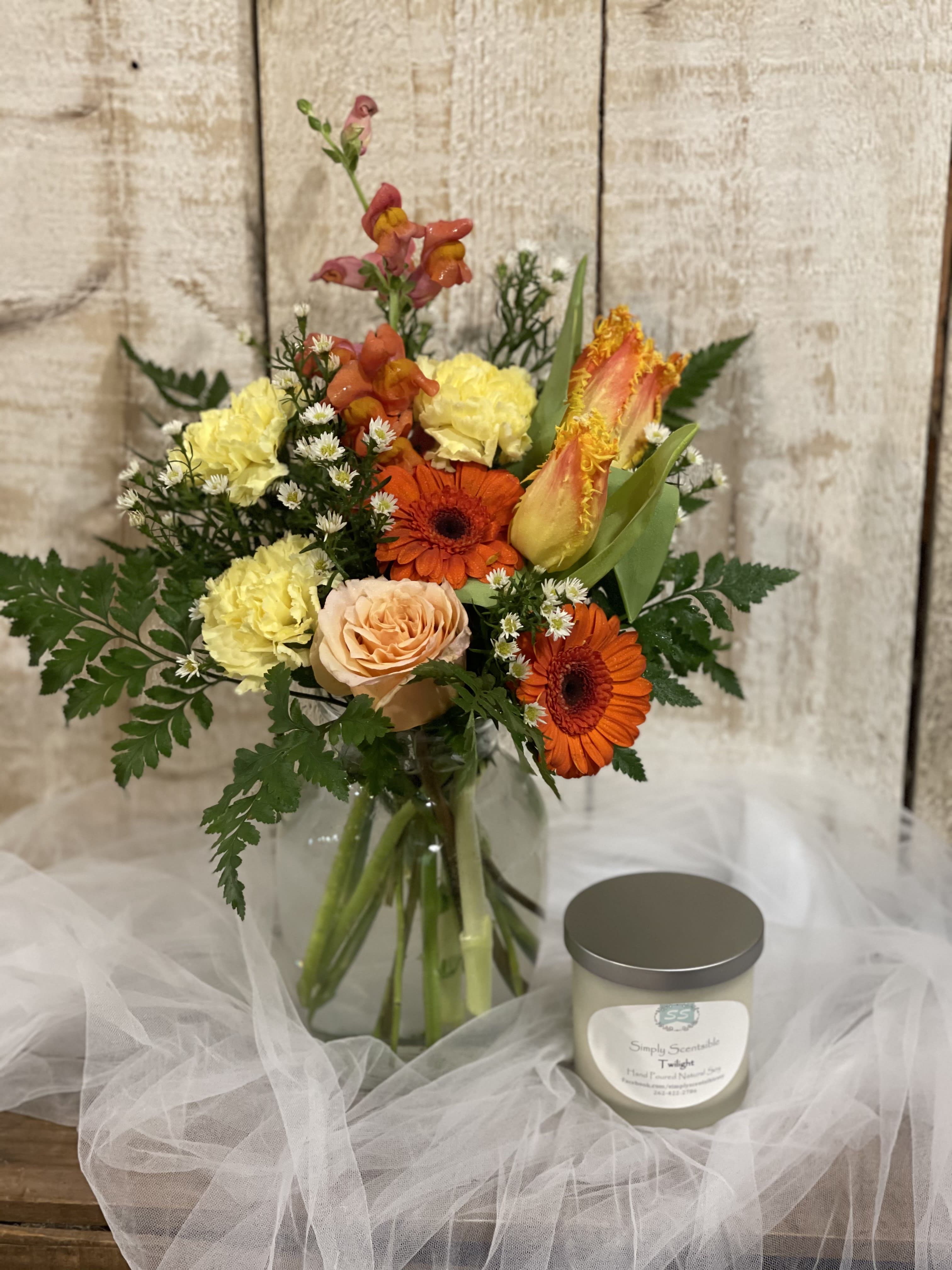 Mixed bouquet in a glass vase beside a scented candle