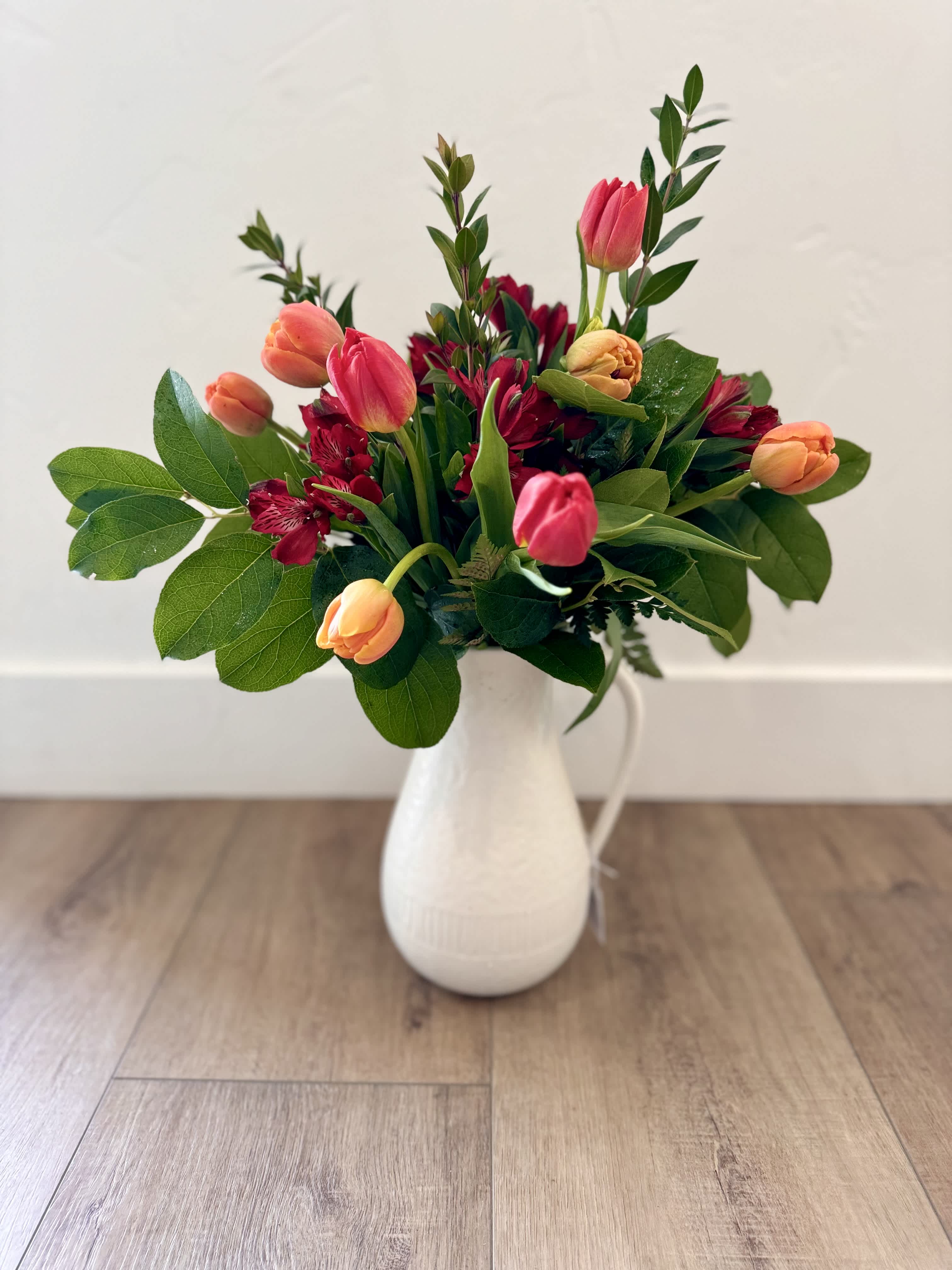 Pink and peach tulips with red blooms in a white vase