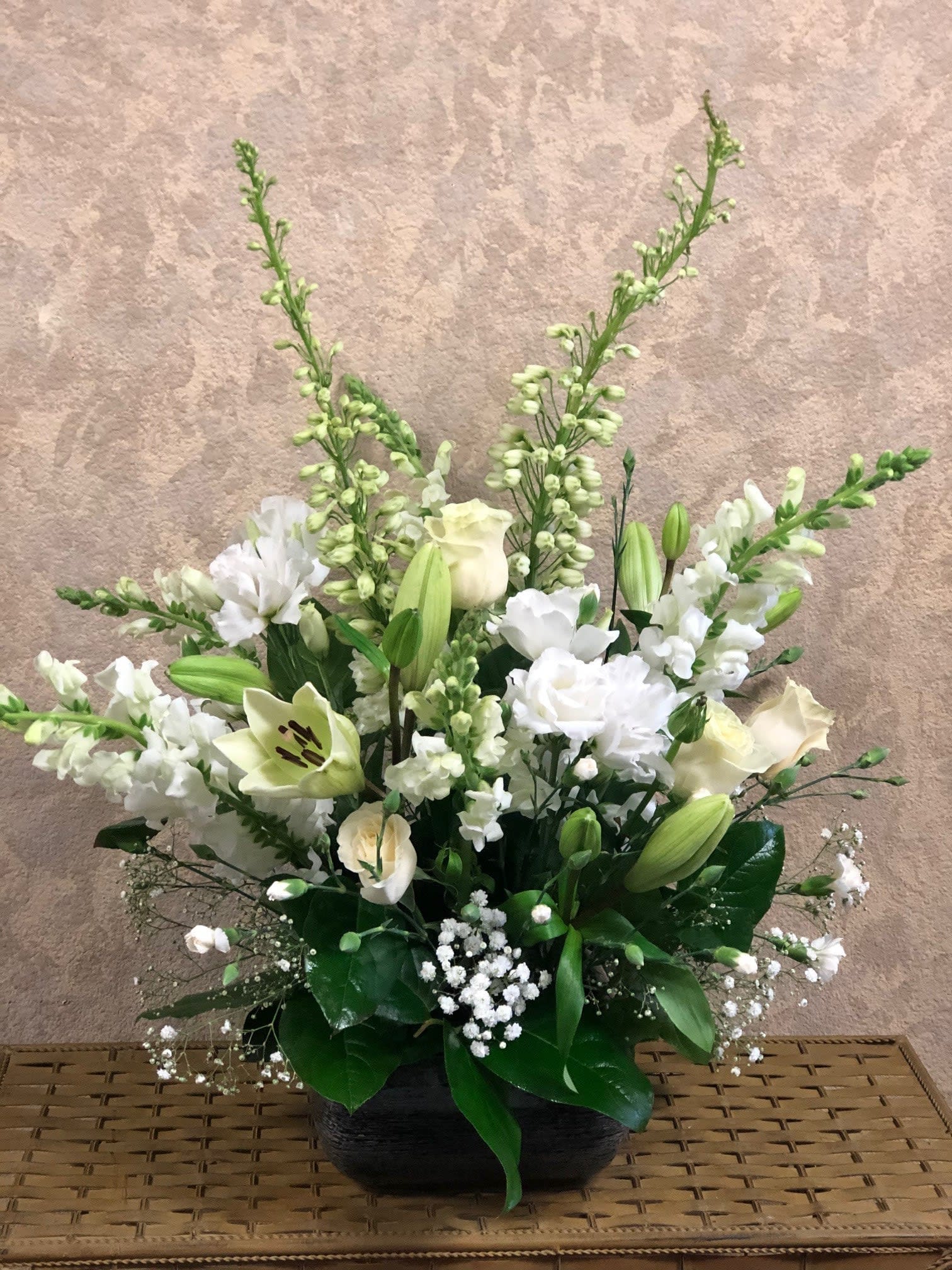 White floral arrangement in a black bowl vase with tall stems