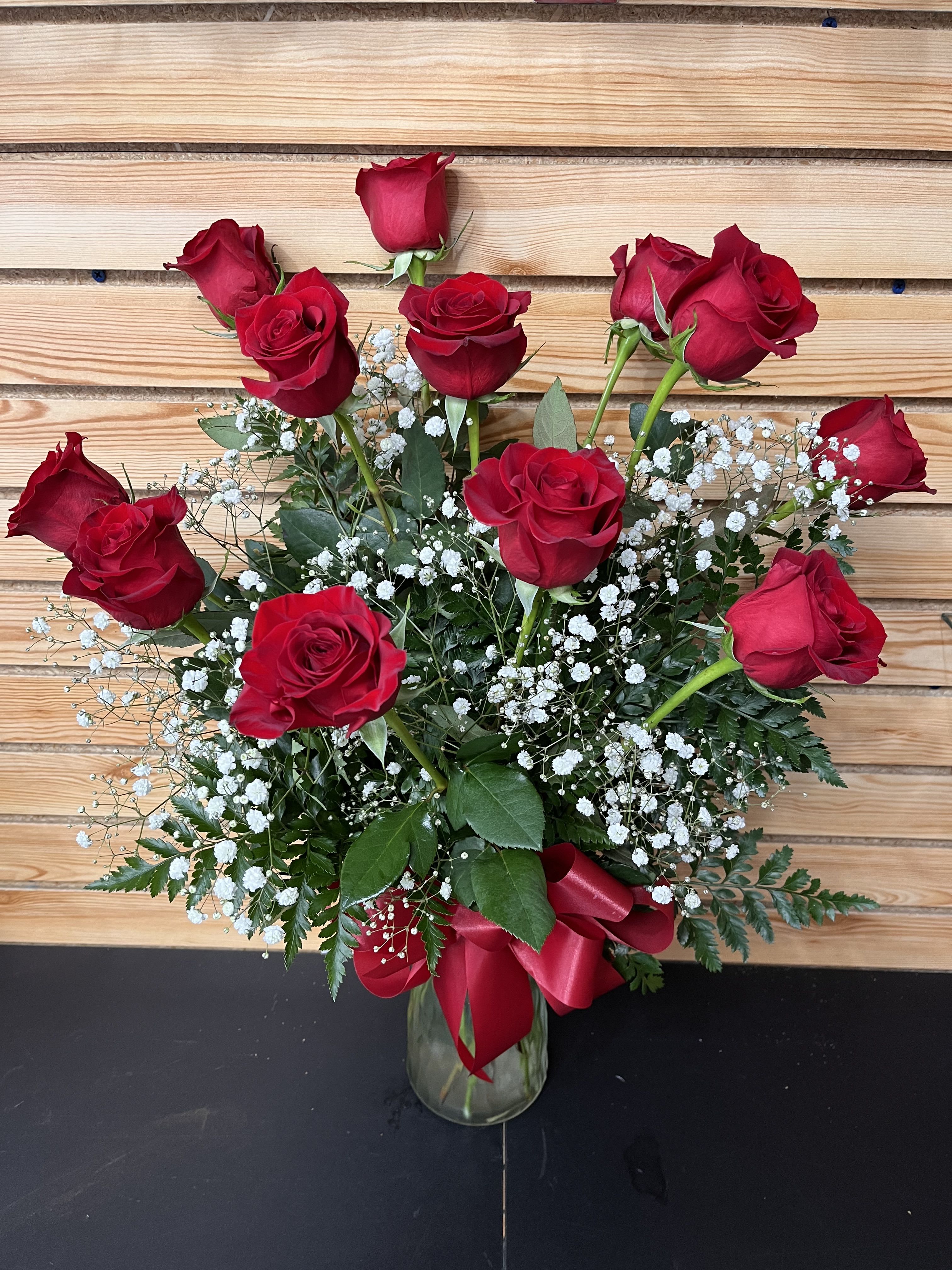 Red roses arranged in a glass vase with white baby's breath