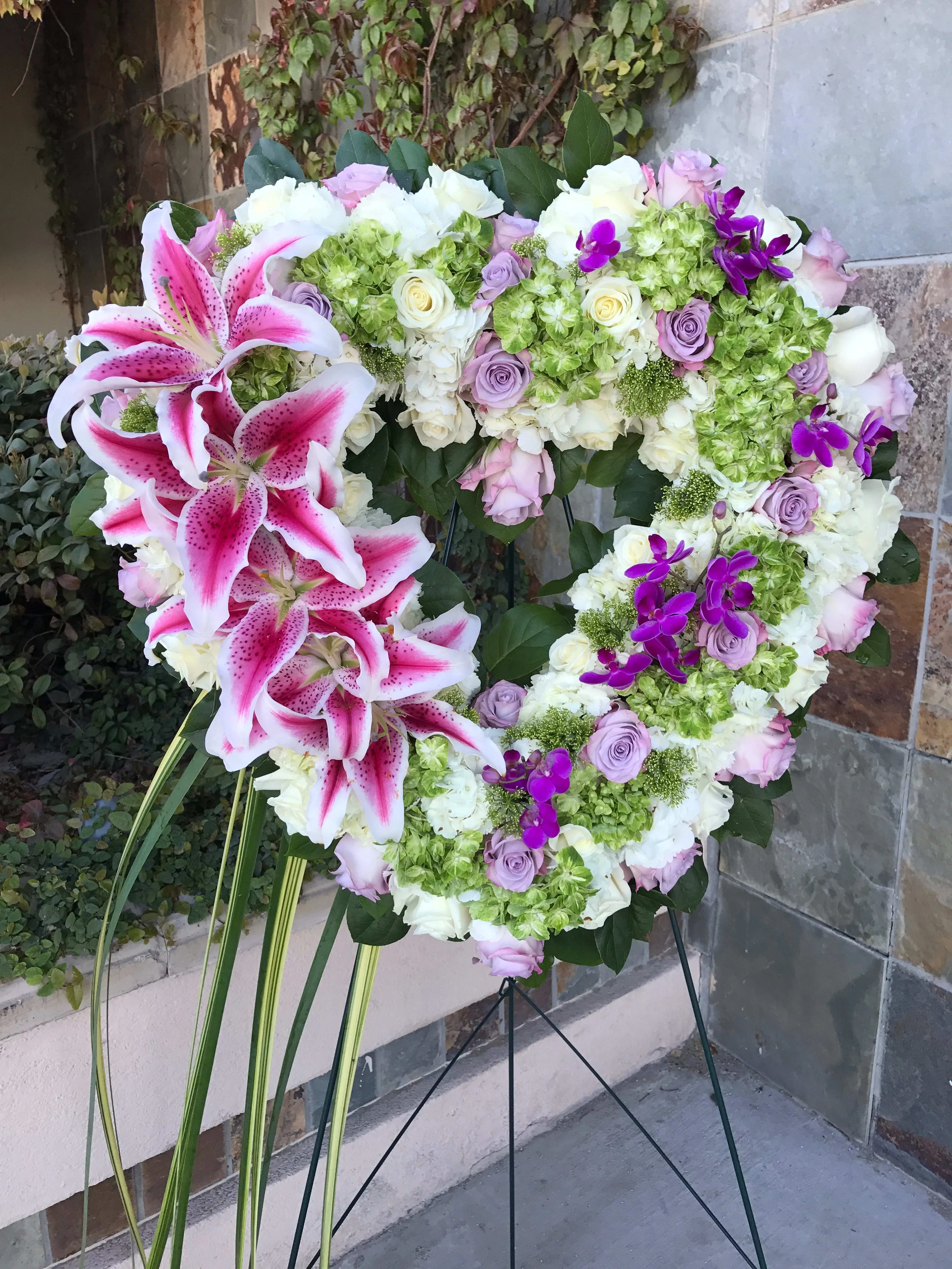 Heart-shaped floral wreath with pink lilies, roses, hydrangeas, and purple orchids